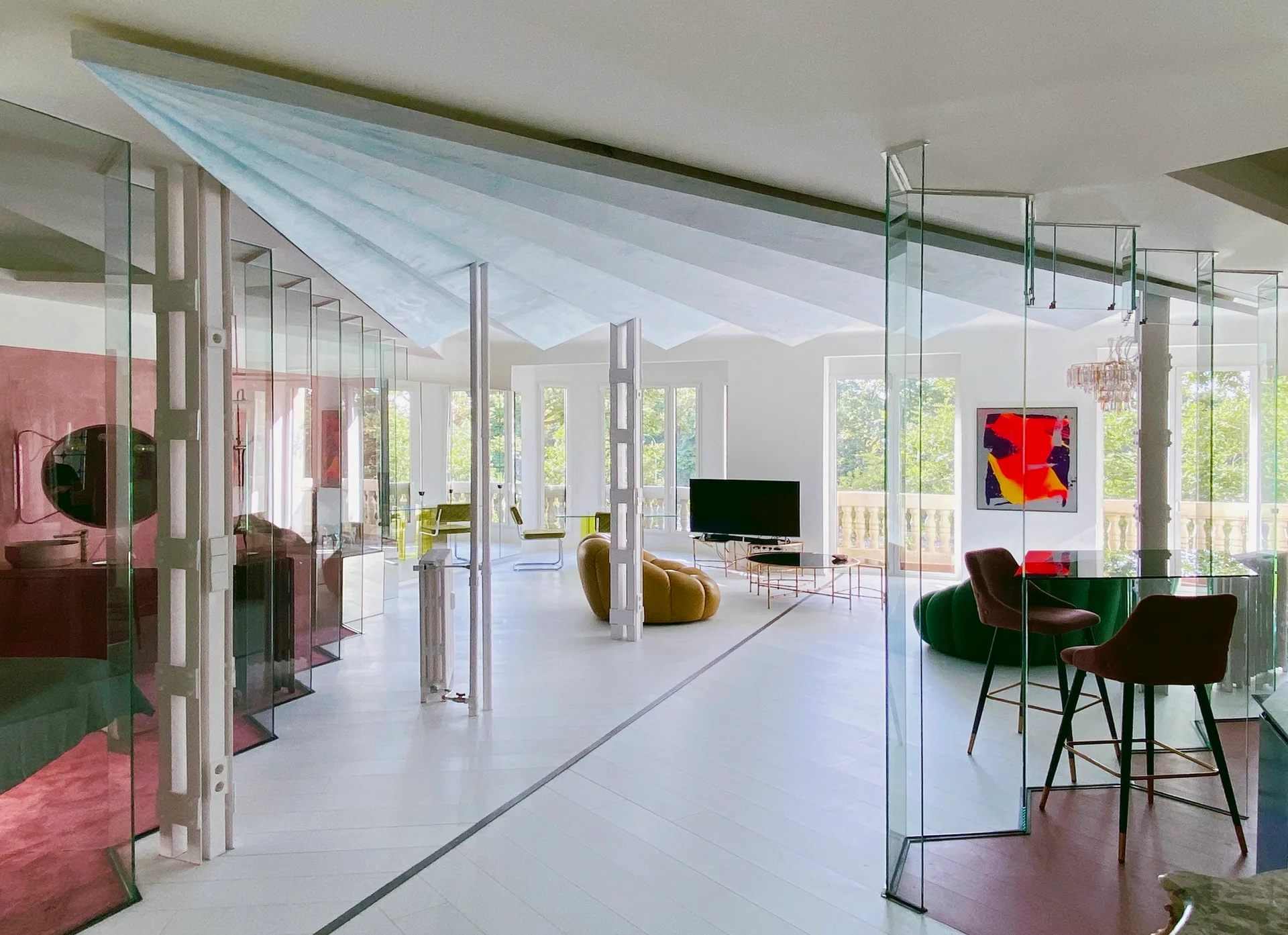 A bright modern living space featuring zigzag glass partition walls, a faceted blue ceiling, and a mustard yellow sofa.
