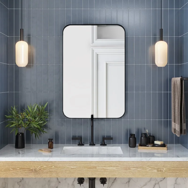A modern bathroom vanity features a white marble sink countertop, a black-framed mirror, and vertical blue wall tiles flanked by two pendant lights.