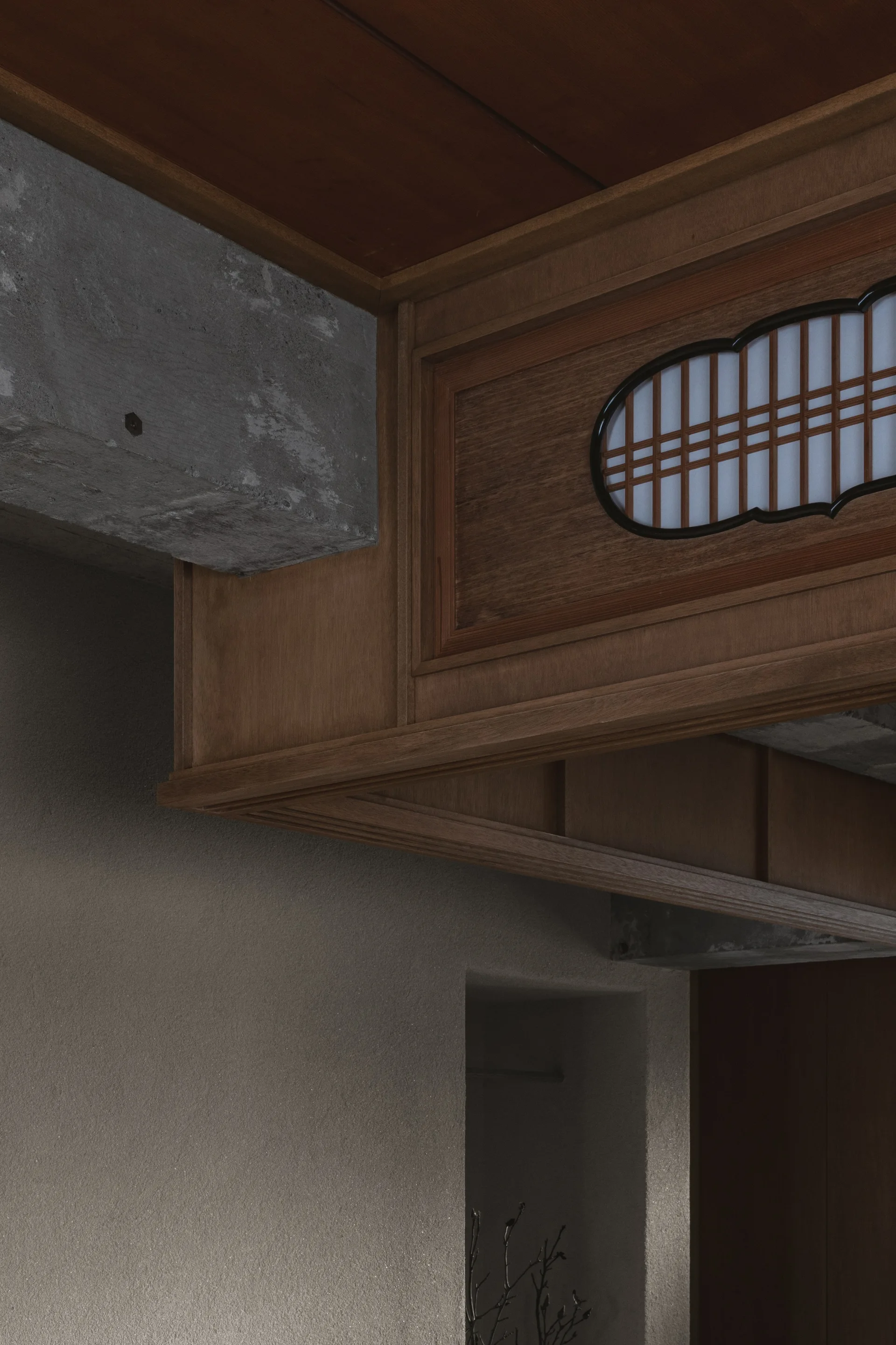 A close-up of an interior architectural detail showing a wooden structure with an oval lattice window beside a raw concrete beam and textured plaster wall.
