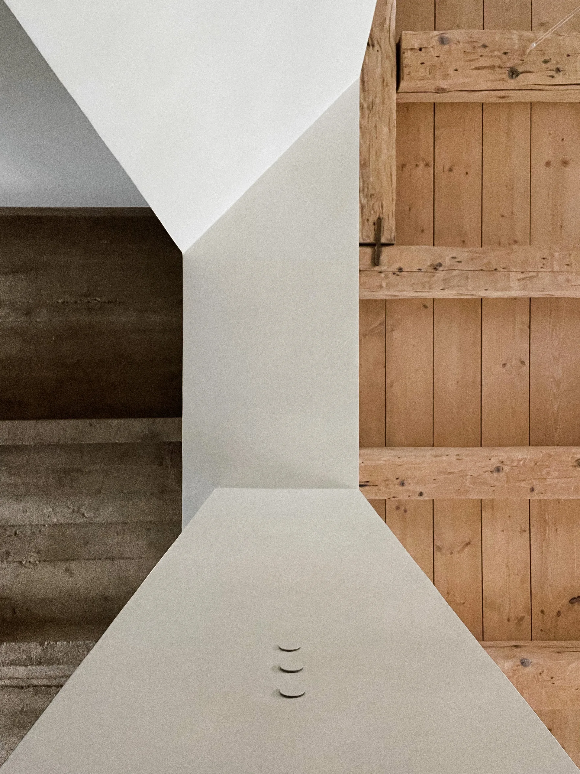 An architectural detail showing a smooth beige plaster structure meeting a rustic wood ceiling with exposed timber planks and beams.