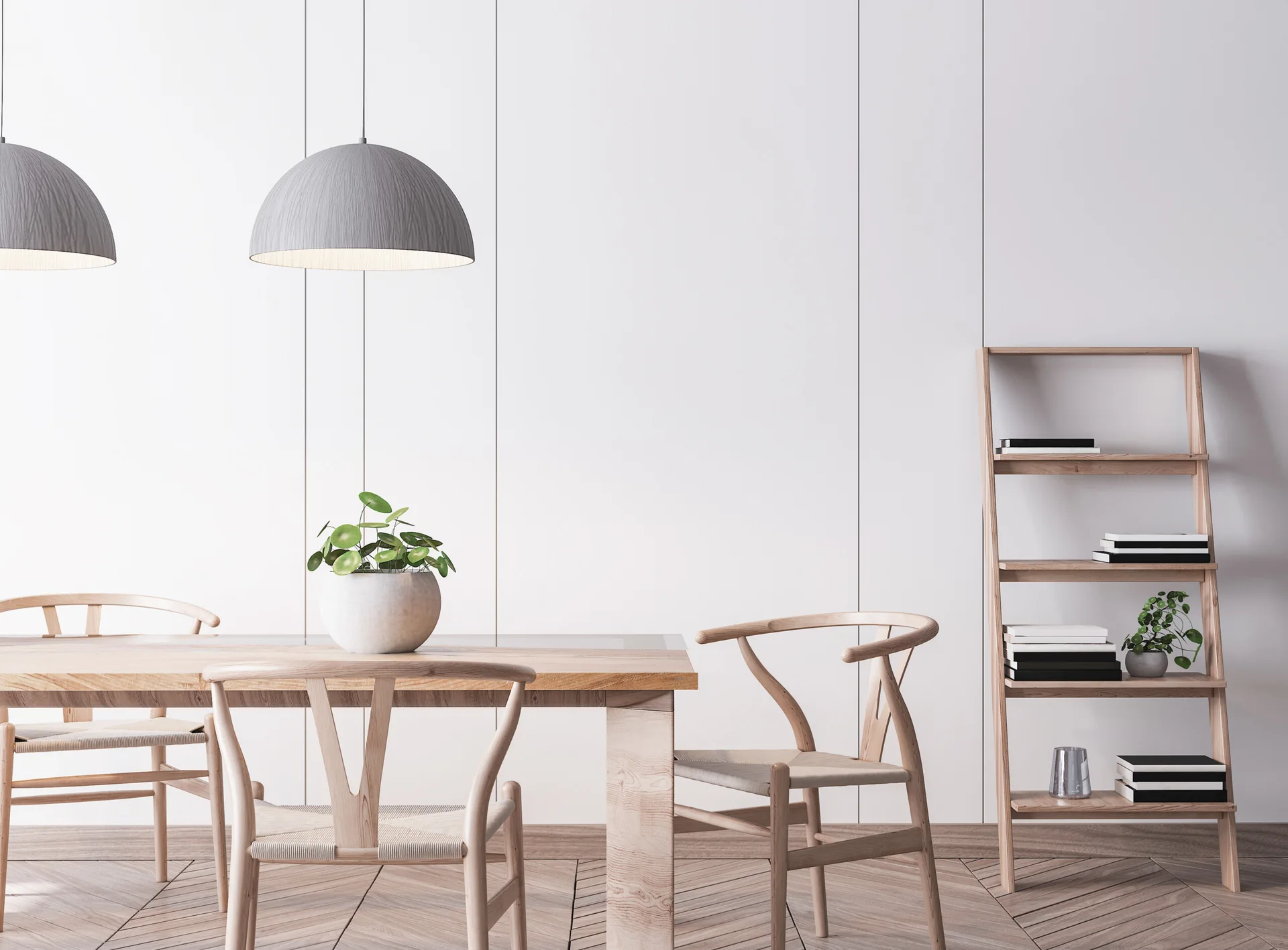 A minimalist dining room features a wooden table, wishbone chairs, gray dome pendant lights, and a ladder bookshelf against white paneled walls.
