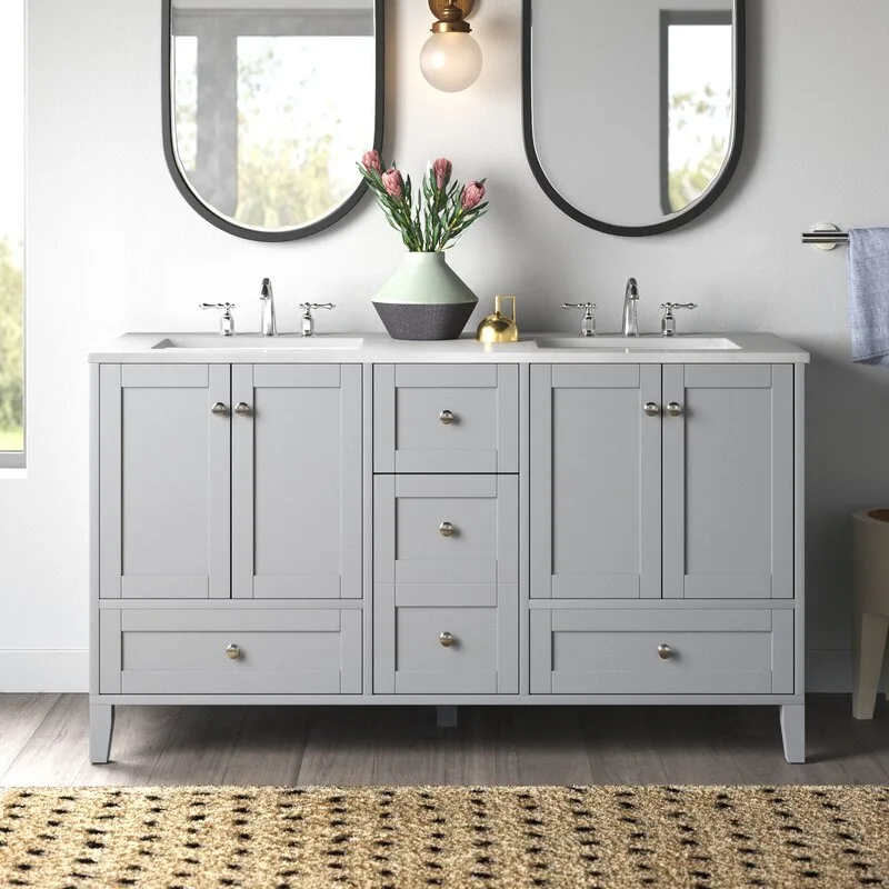 A light grey double vanity features two integrated sinks with silver faucets, set beneath two matching black-framed oval mirrors on a white wall.