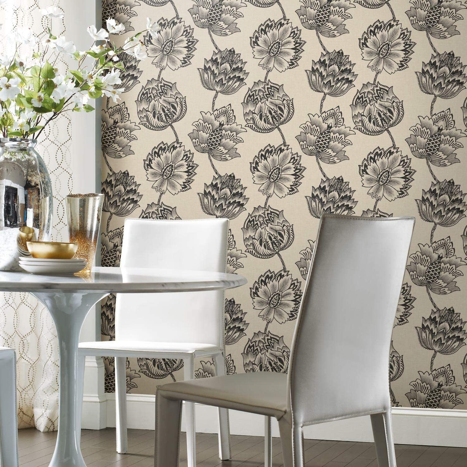A modern white dining table and chairs set against a wall featuring black and beige botanical floral wallpaper.