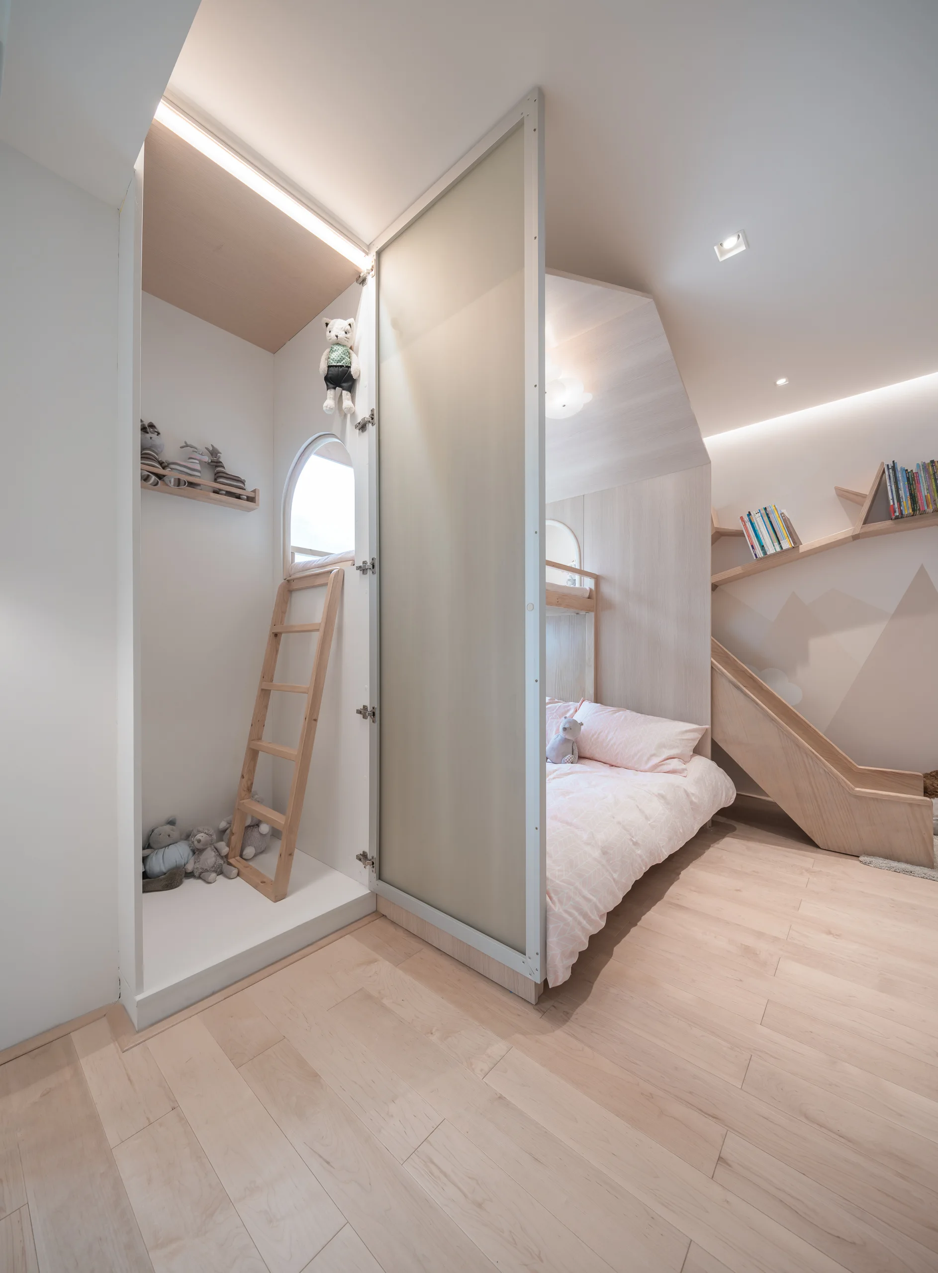 A children's bedroom features a light wood built-in bed with a slide, a climbing ladder in an alcove, and a frosted glass partition.