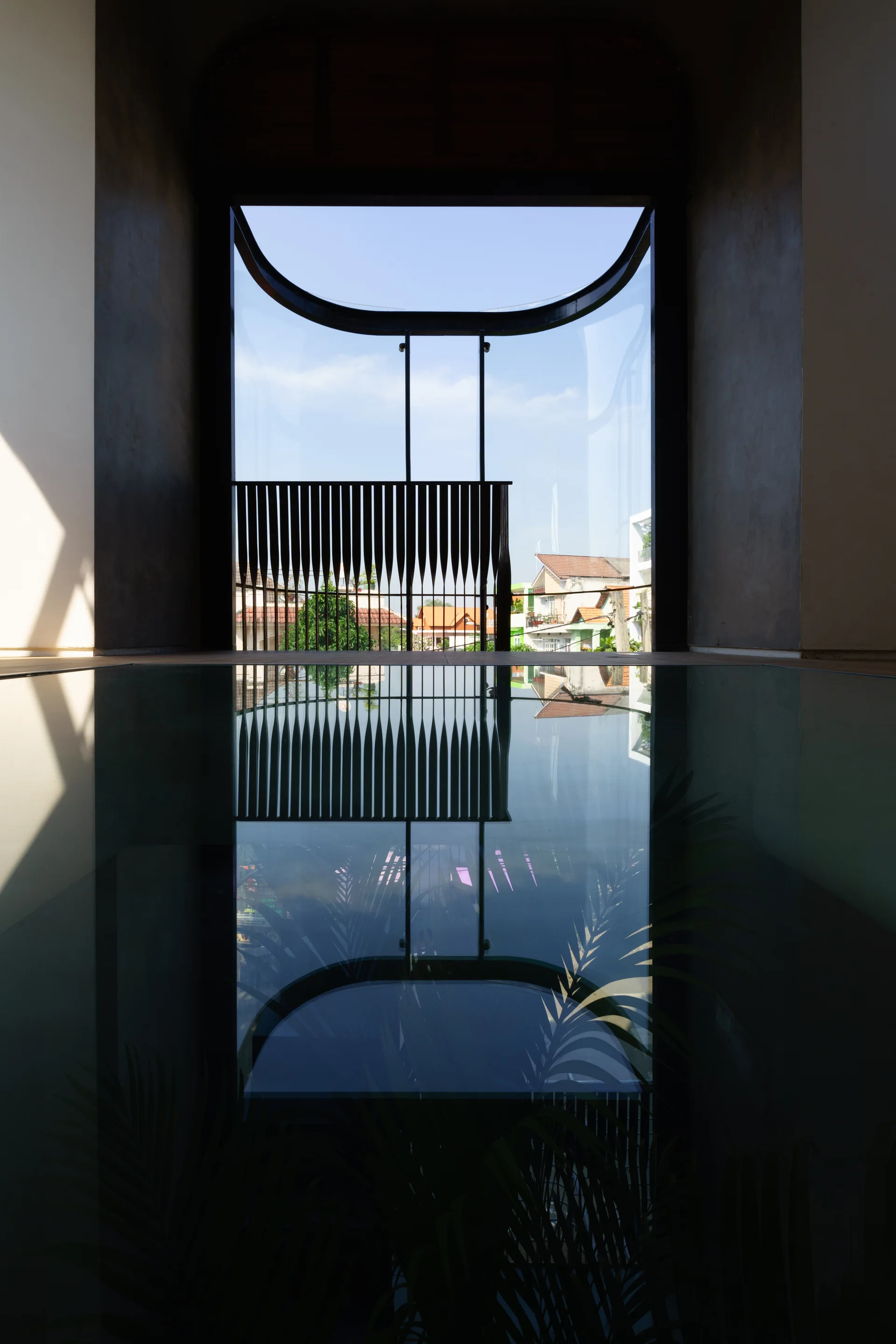 A modern architectural landing features a large curved window reflecting perfectly onto a dark polished floor.