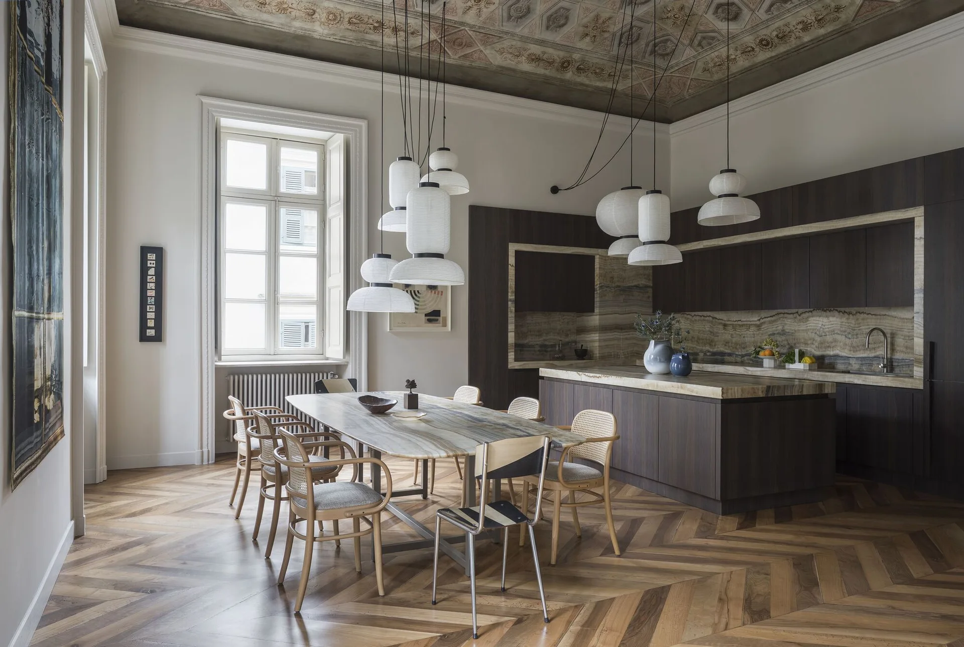 A spacious kitchen and dining area with a stone-topped table, dark wood cabinets, and an intricately painted decorative ceiling.
