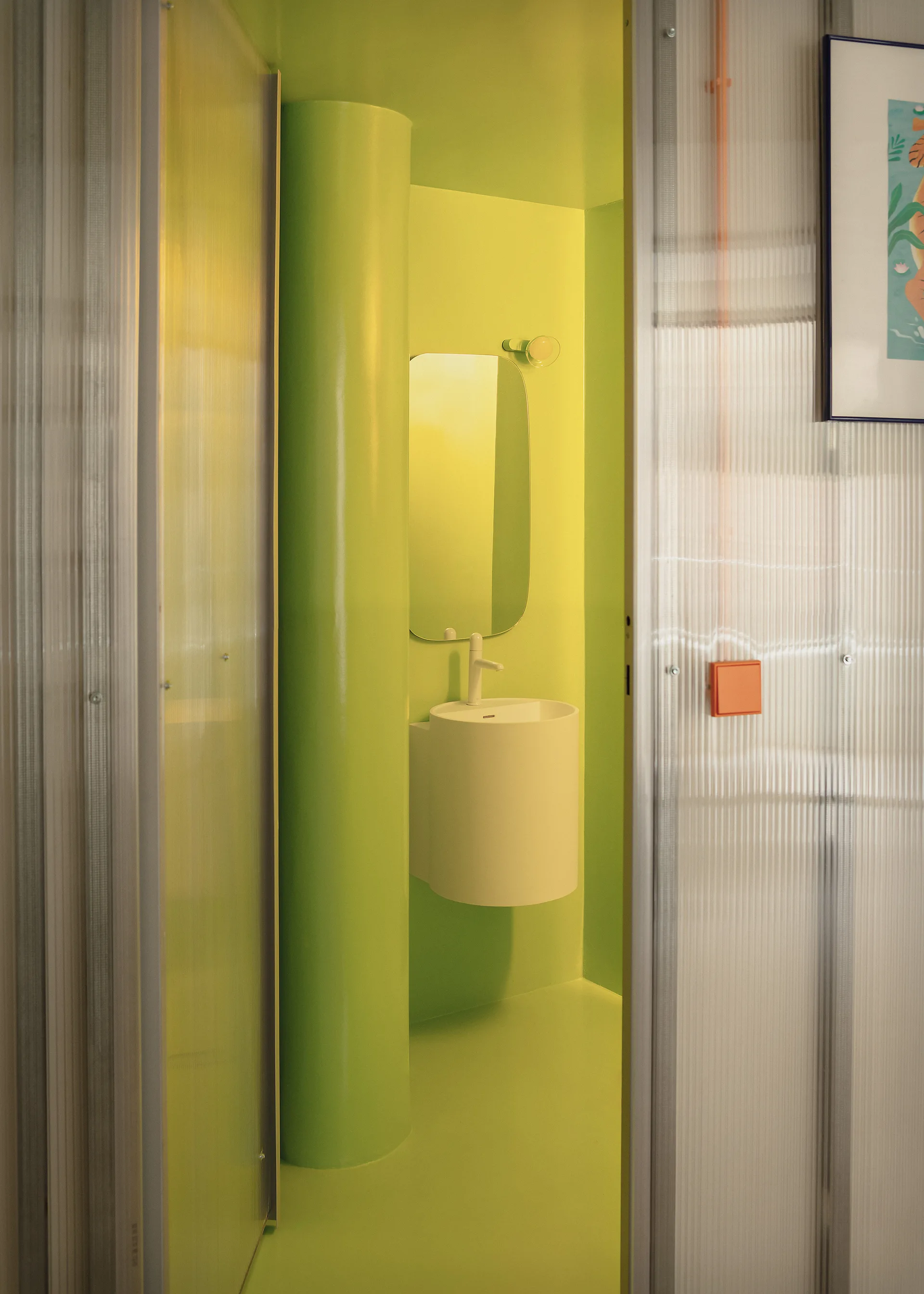 A minimalist bathroom features glossy lime green walls and floor, a white wall-mounted curved sink with a mirror, and a translucent corrugated door.