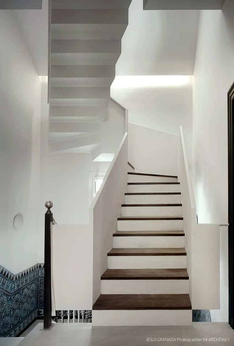 A modern white staircase features dark wood treads, solid white balustrades, and a decorative blue and white patterned tile wall at the base.