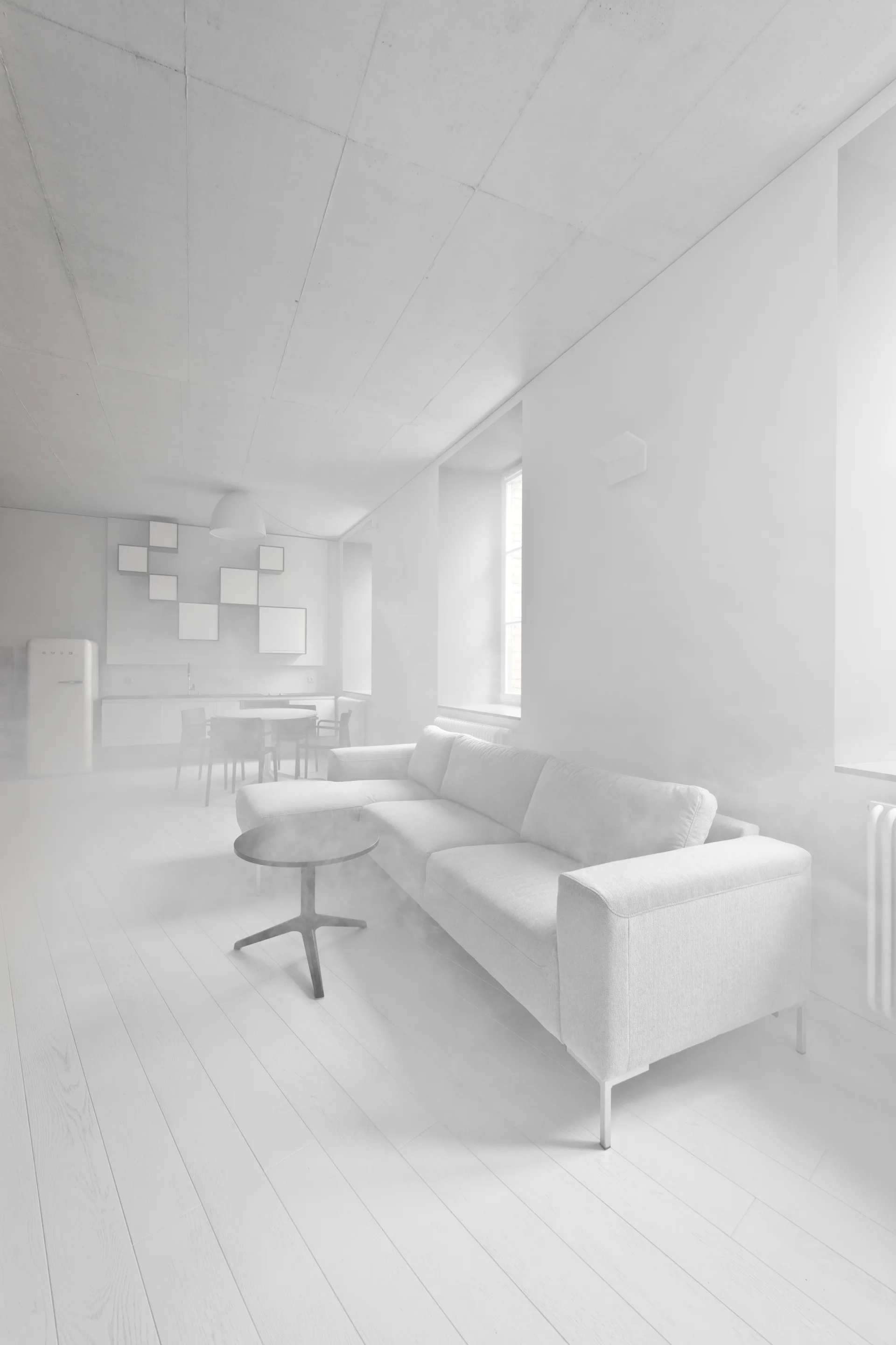 A minimalist all-white open-plan living room features a modern sectional sofa, a small round coffee table, and a distant dining area.