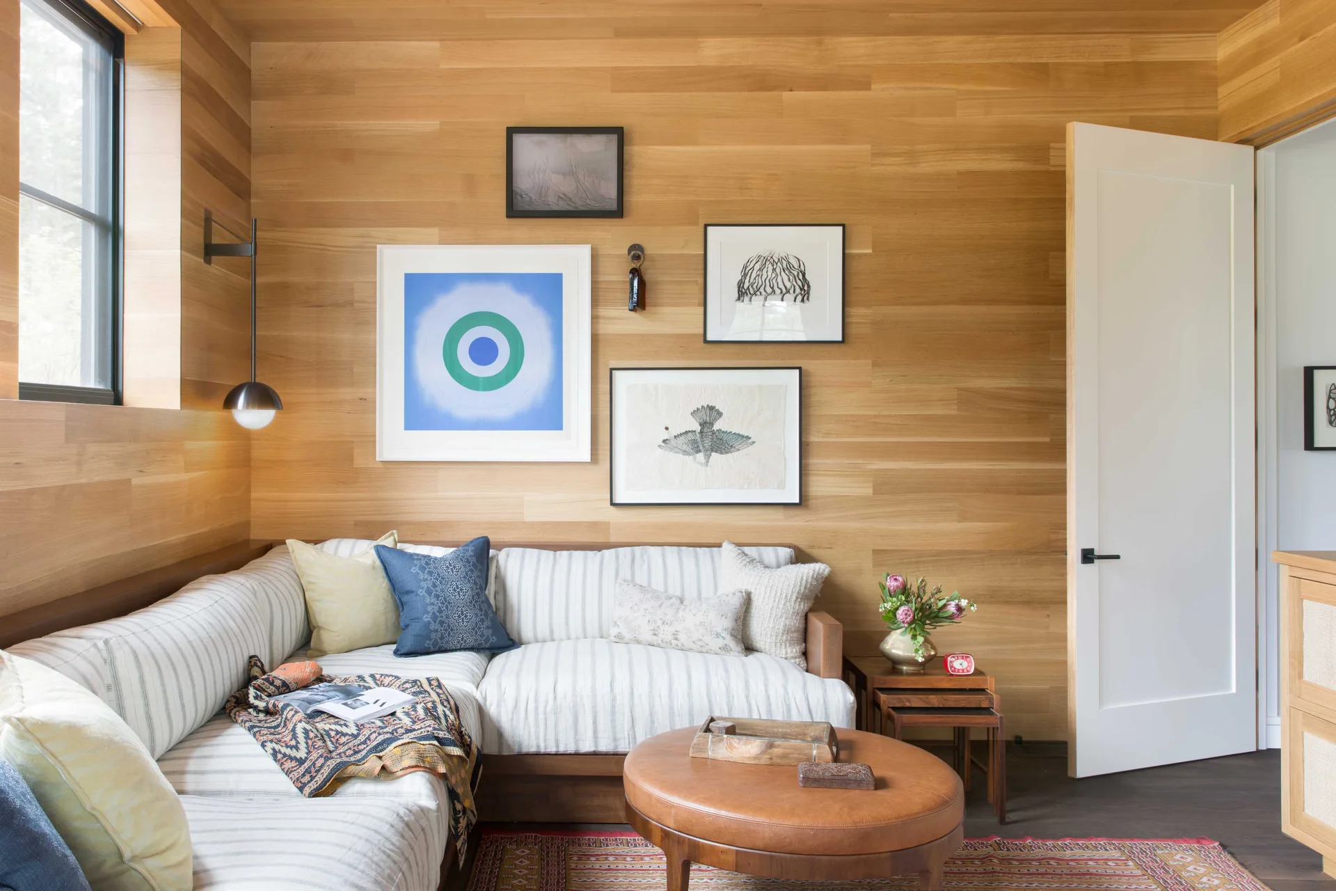 A striped sectional sofa is tucked into a corner with horizontal wood paneling and a small gallery wall of framed artwork.