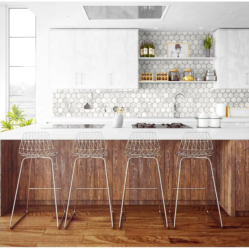 Four wire-frame bar stools sit at a white countertop kitchen island with rustic wood paneling against a hexagonal tiled backsplash wall.
