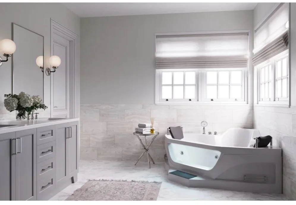 A modern classic bathroom featuring a light grey vanity, a corner jetted bathtub under double windows, and horizontal stone tile wall wainscoting.