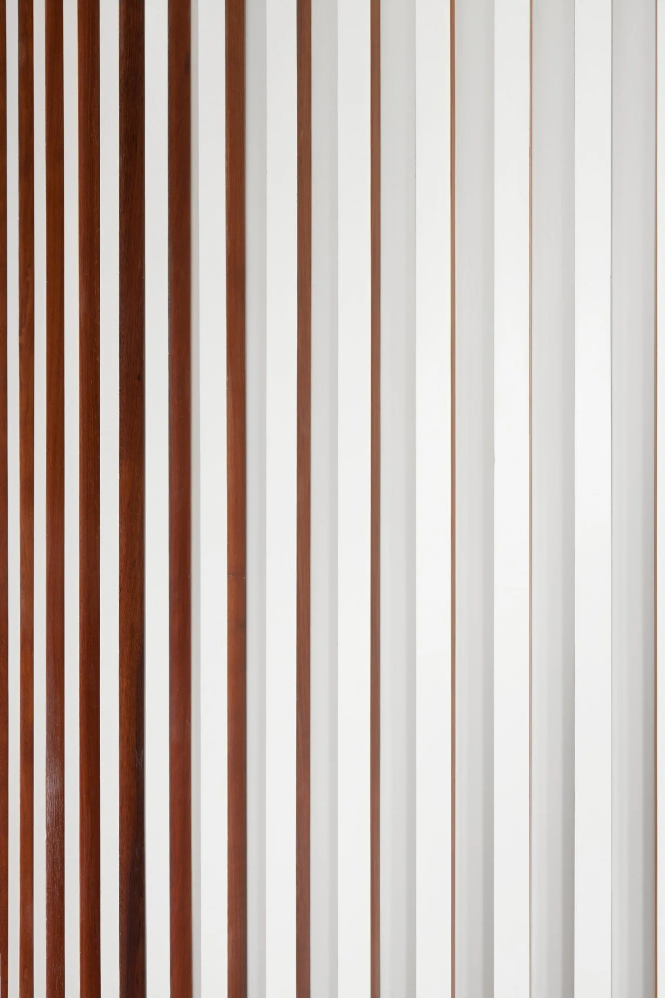 A close-up view of wall paneling featuring alternating vertical brown wood and matte white slats.