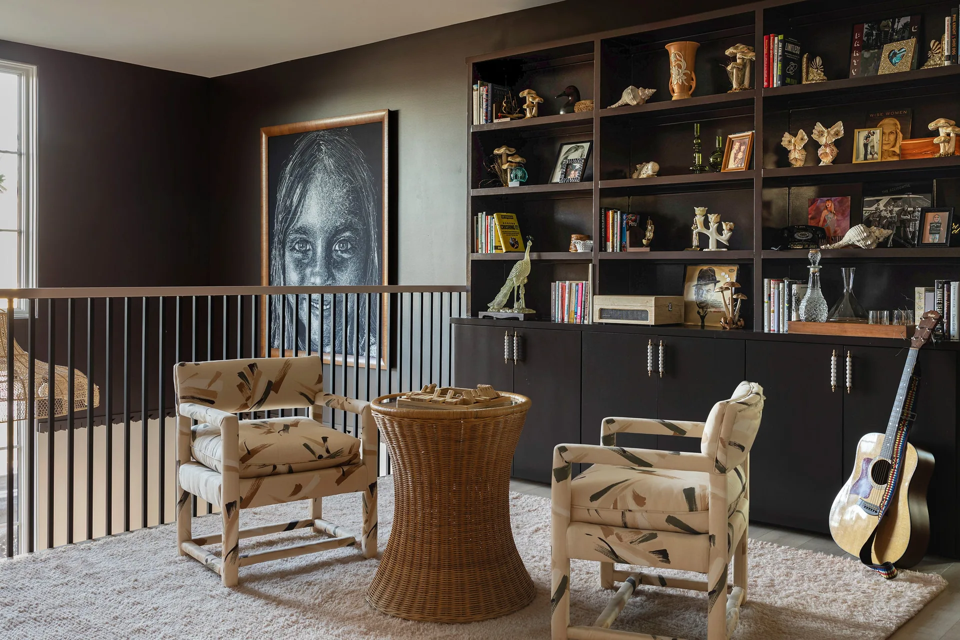 A landing seating area features two patterned armchairs, a rattan side table, a shag rug, and a large dark charcoal built-in bookshelf.