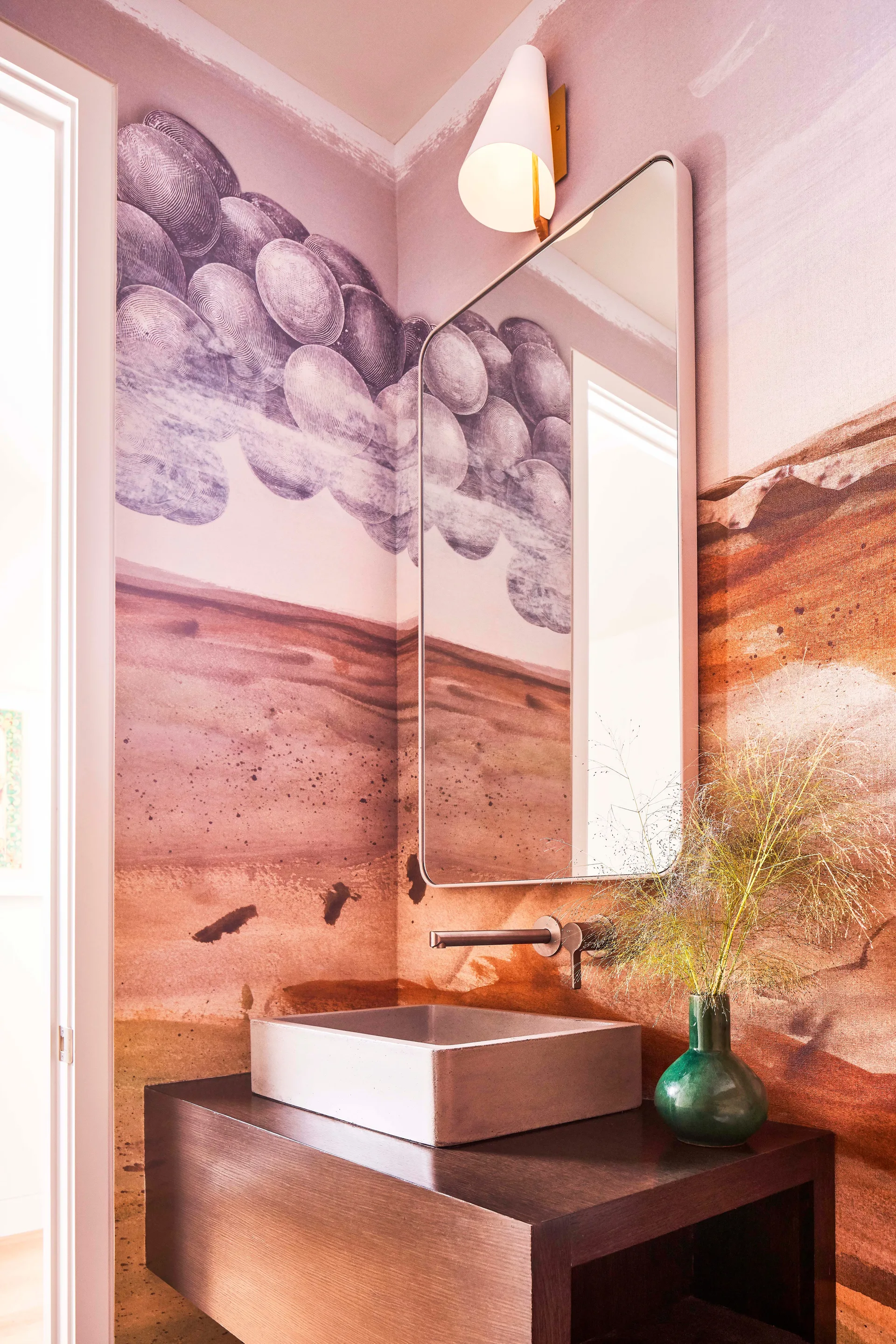 A powder room featuring a concrete vessel sink on a dark wood vanity, backed by a terracotta and purple abstract mural wall.
