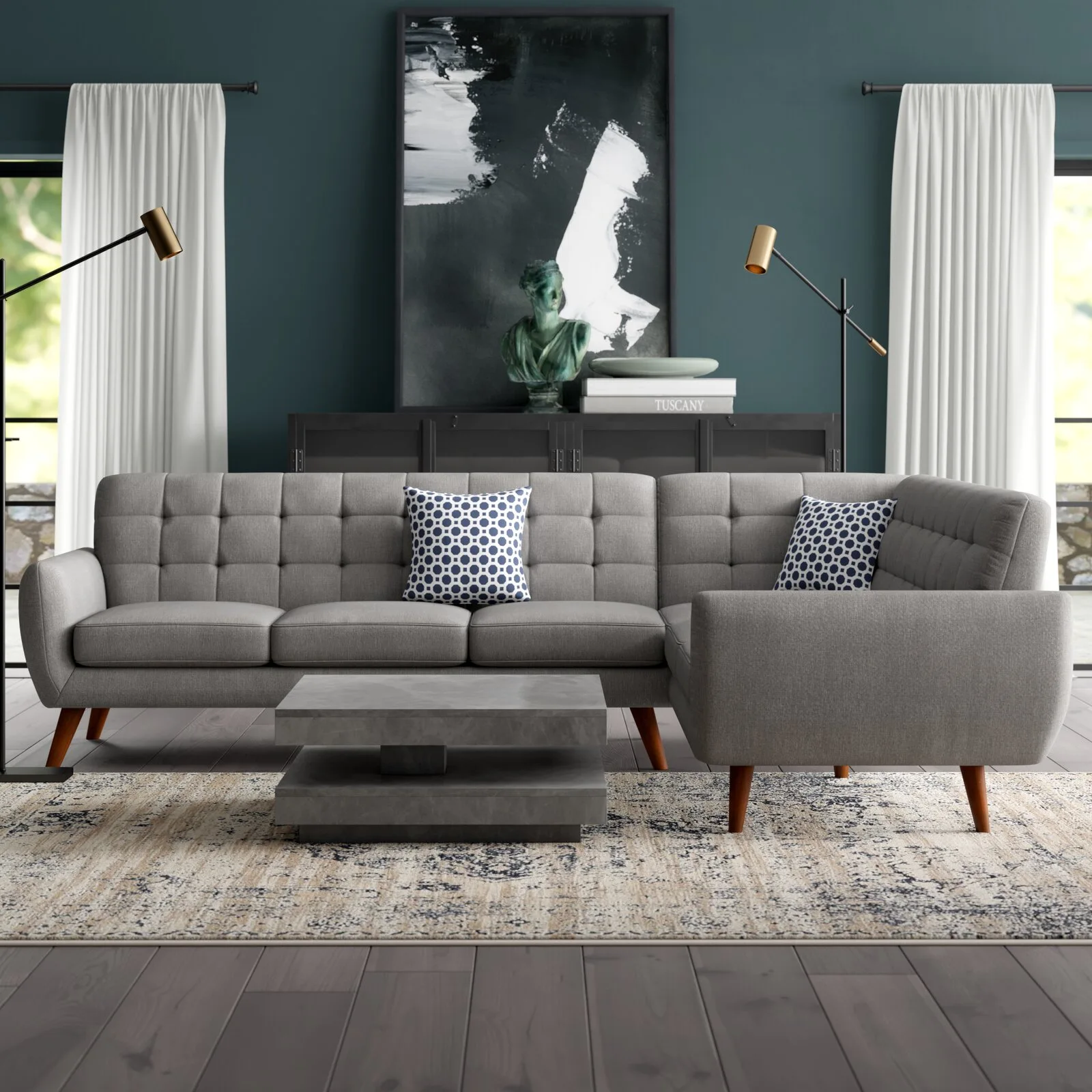 A grey tufted sectional sofa sits on a patterned rug in front of a dark teal wall decorated with large abstract artwork.