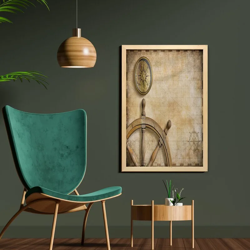 A teal upholstered lounge chair stands next to a light wood side table against a dark green painted wall with framed nautical artwork.