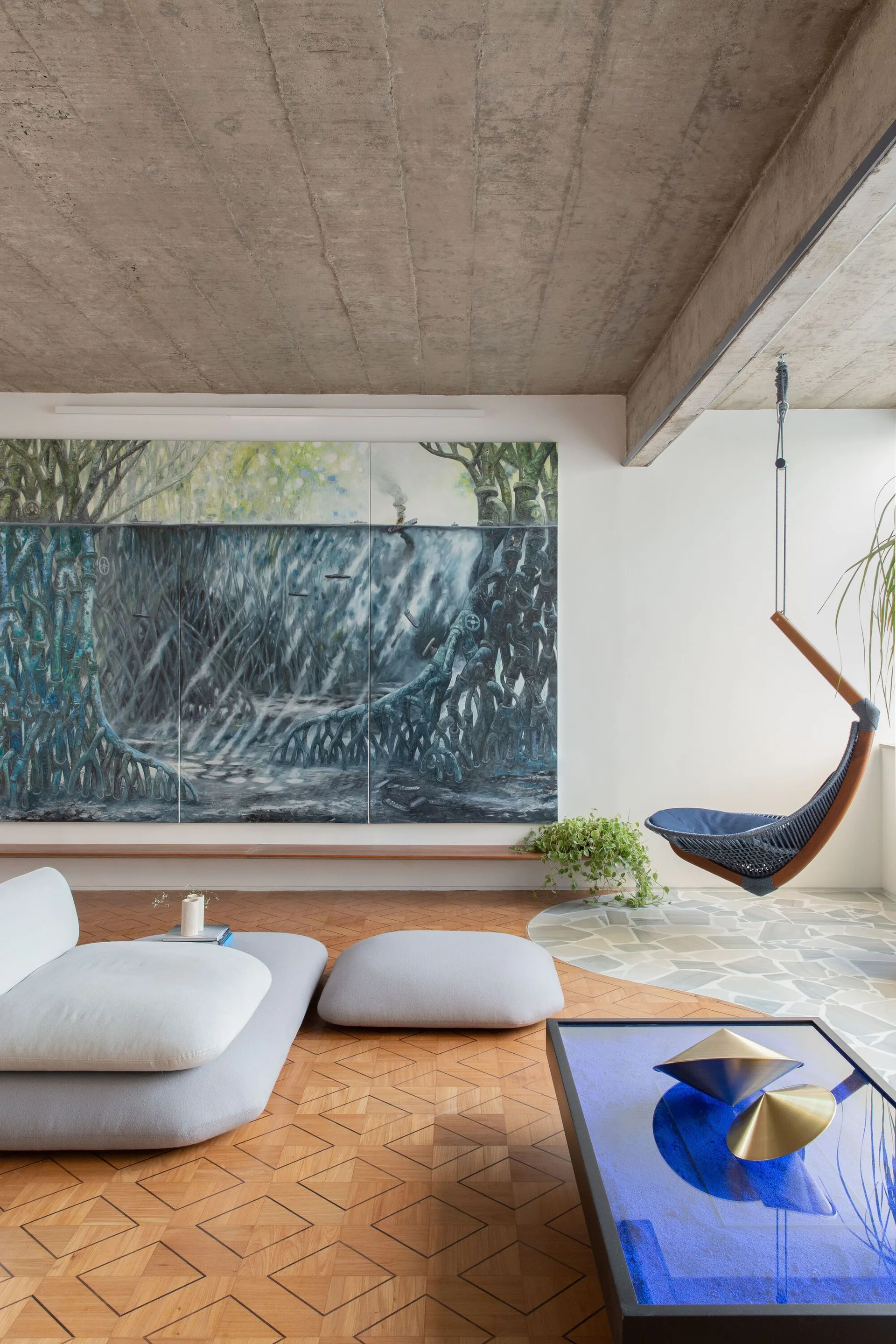 A modern living room features a textured concrete ceiling, a geometric patterned wood floor, a large landscape painting, and a suspended hanging chair.