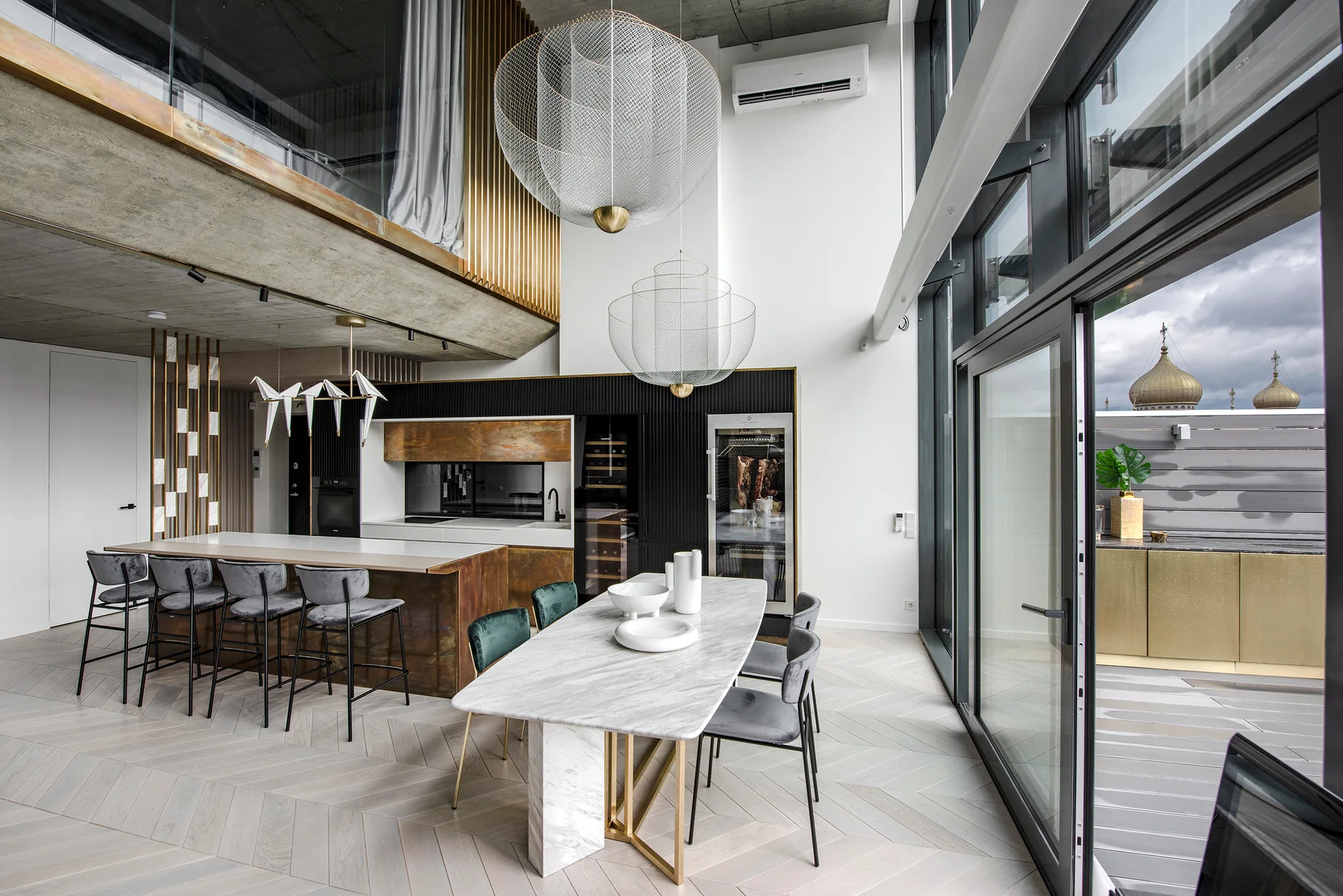A double-height modern kitchen and dining room features large wire mesh pendant lights, a marble dining table with grey velvet chairs, and a kitchen island.