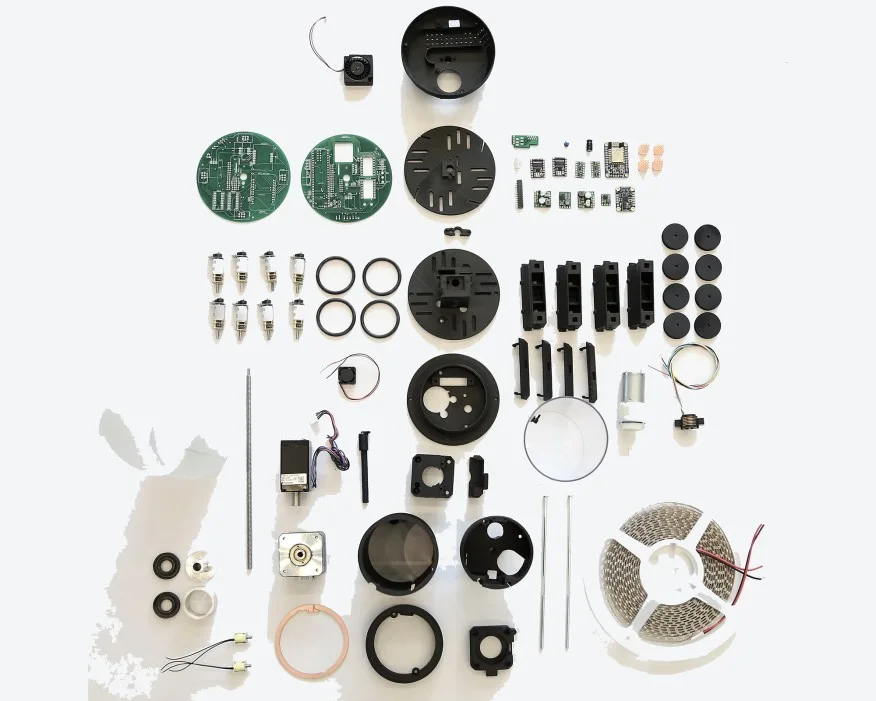 A knolling arrangement of electronic components, including green circuit boards, black plastic casings, and a coiled LED strip on a white surface.