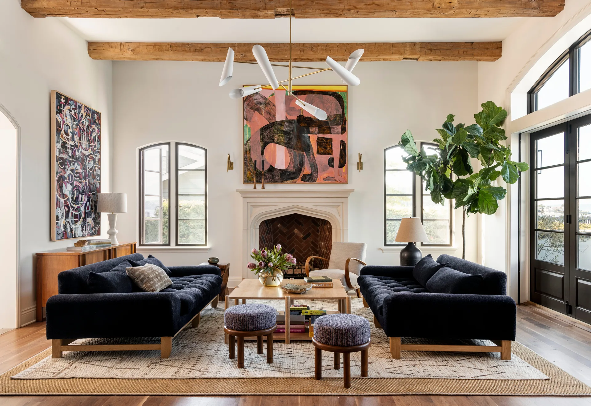 A symmetrical living room features two navy blue sofas facing each other around a wooden coffee table in front of a stone fireplace.