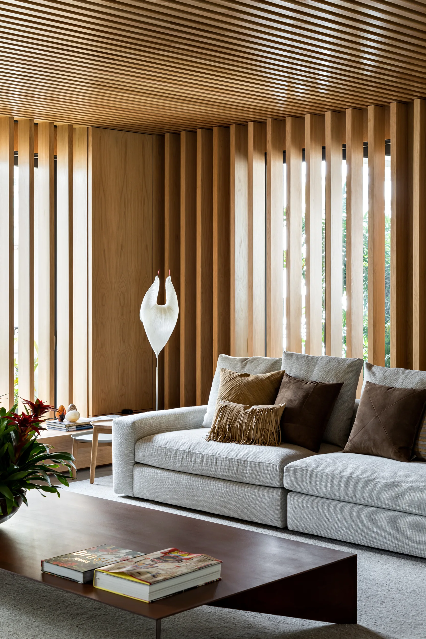 A grey fabric sofa sits in front of natural wood slatted walls and a matching wood slat ceiling.