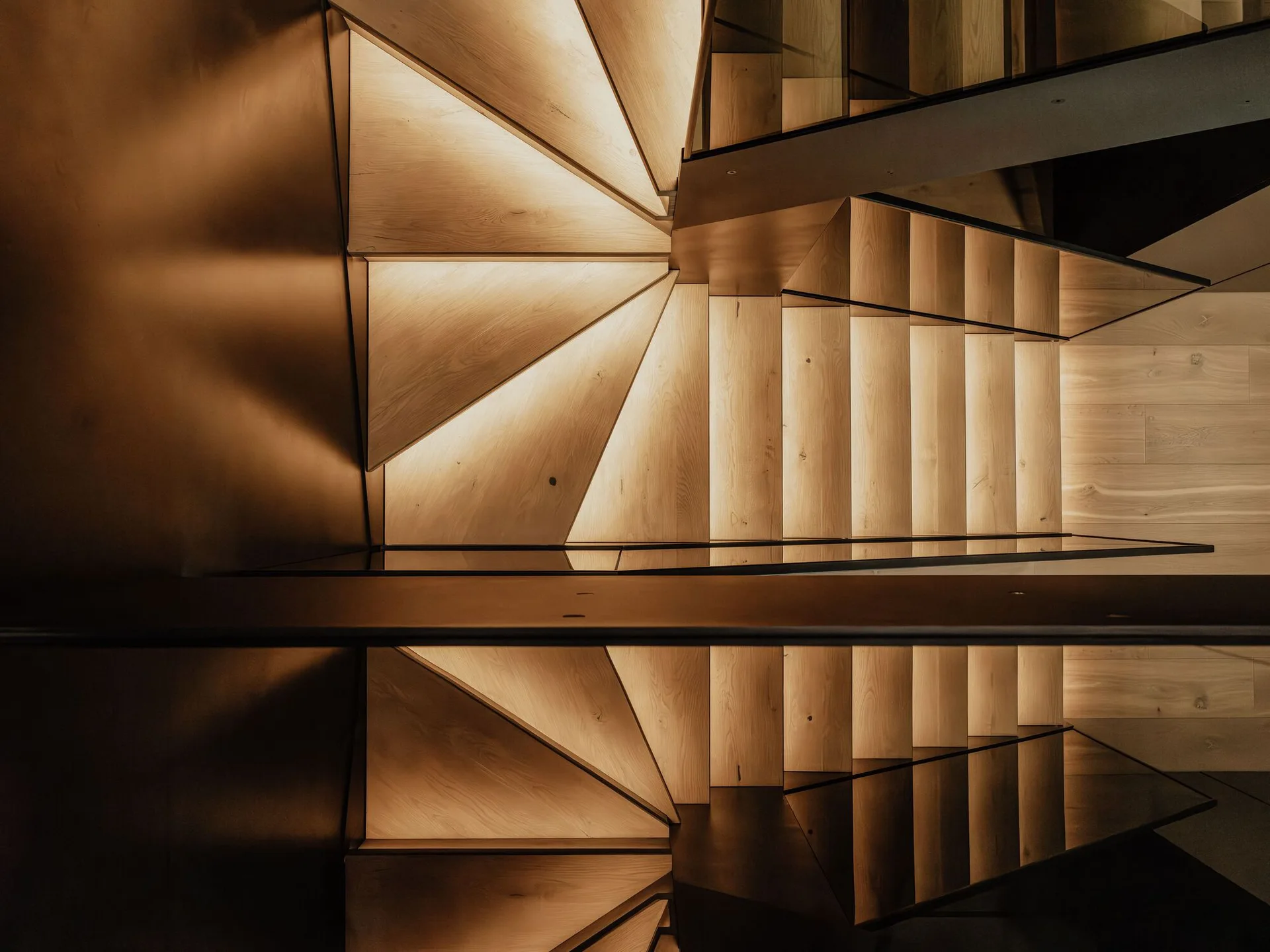An overhead view of a modern wooden staircase featuring light-toned wood steps illuminated from underneath by integrated glowing LED lights.