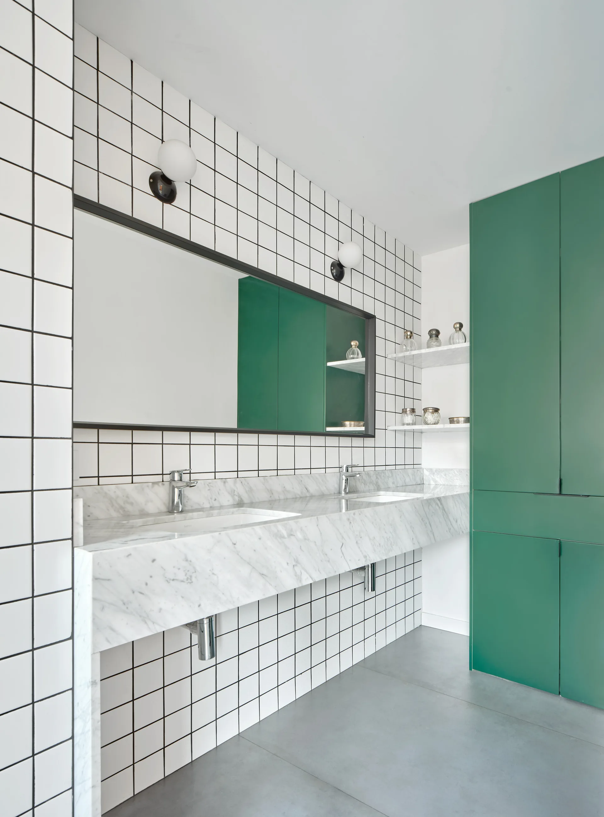 A modern bathroom features a double marble sink vanity, white square grid wall tile, and a tall green cabinet.
