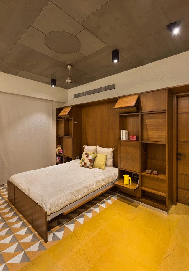 A bedroom featuring a bed integrated into a floor-to-ceiling wooden storage unit with geometric yellow and grey tiled flooring.