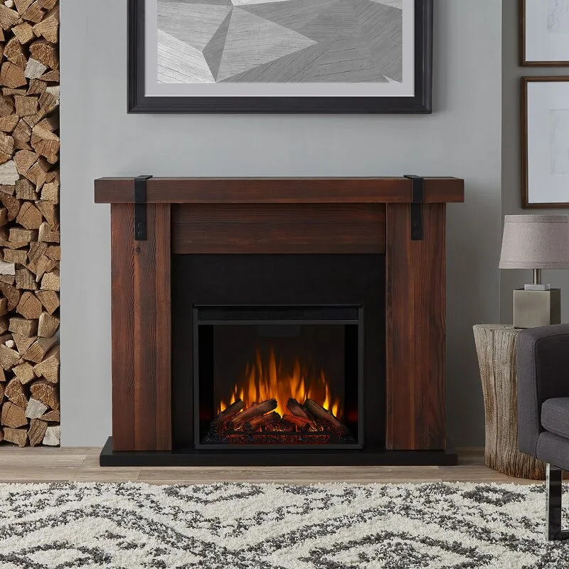 An electric fireplace with a dark rustic wood mantel next to a vertical built-in niche filled with stacked firewood.