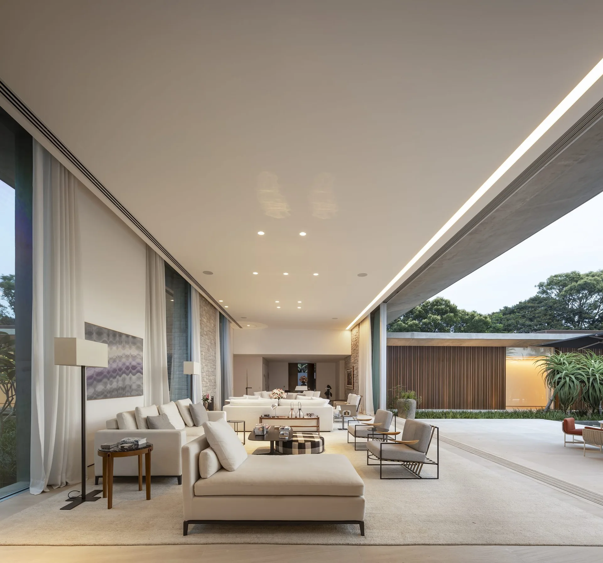 A spacious living room with cream sectional sofas, a stone wall, and sliding glass doors that open to an outdoor patio.