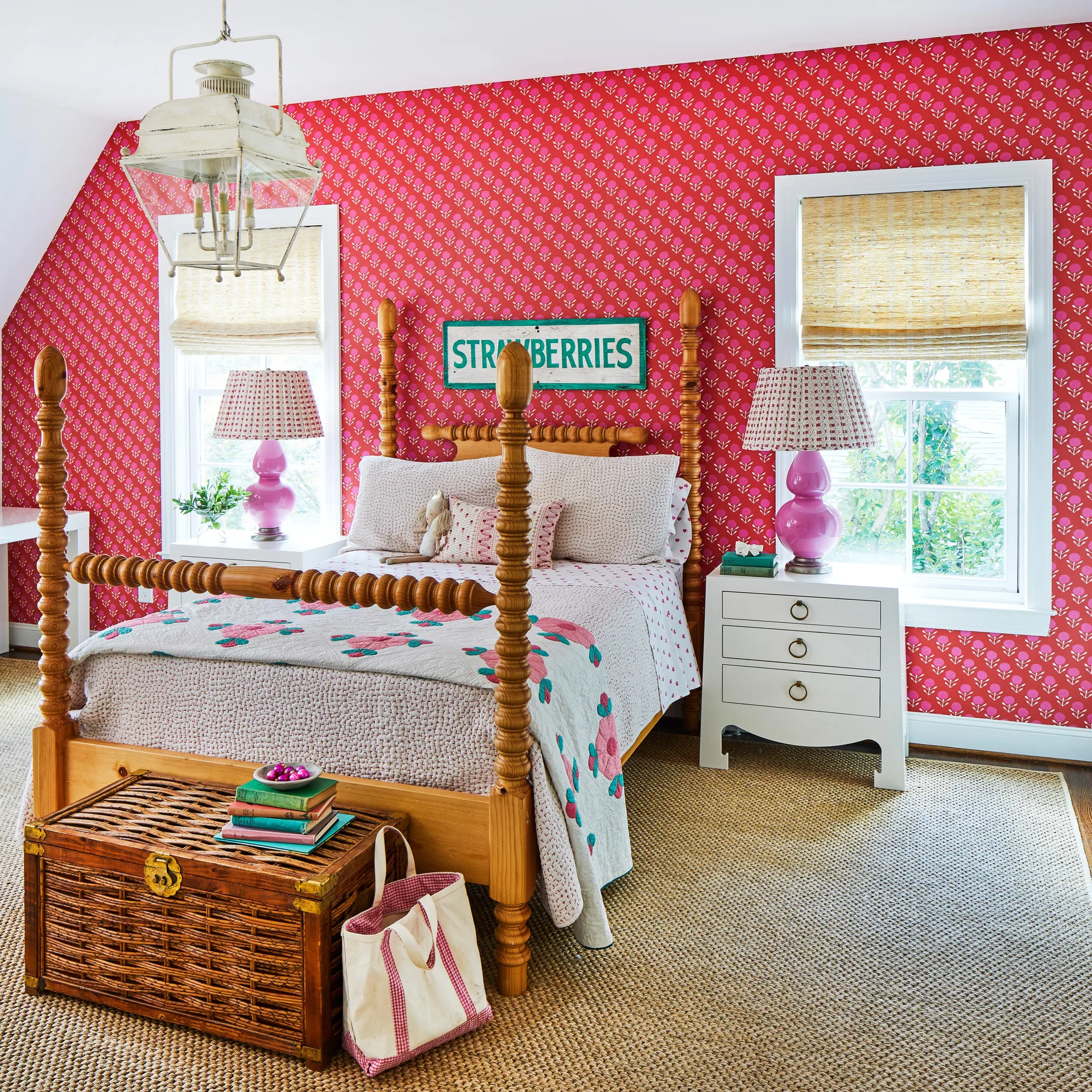 A bedroom featuring a wooden spindle bed set against vibrant pink floral wallpaper, flanked by white nightstands with pink table lamps.