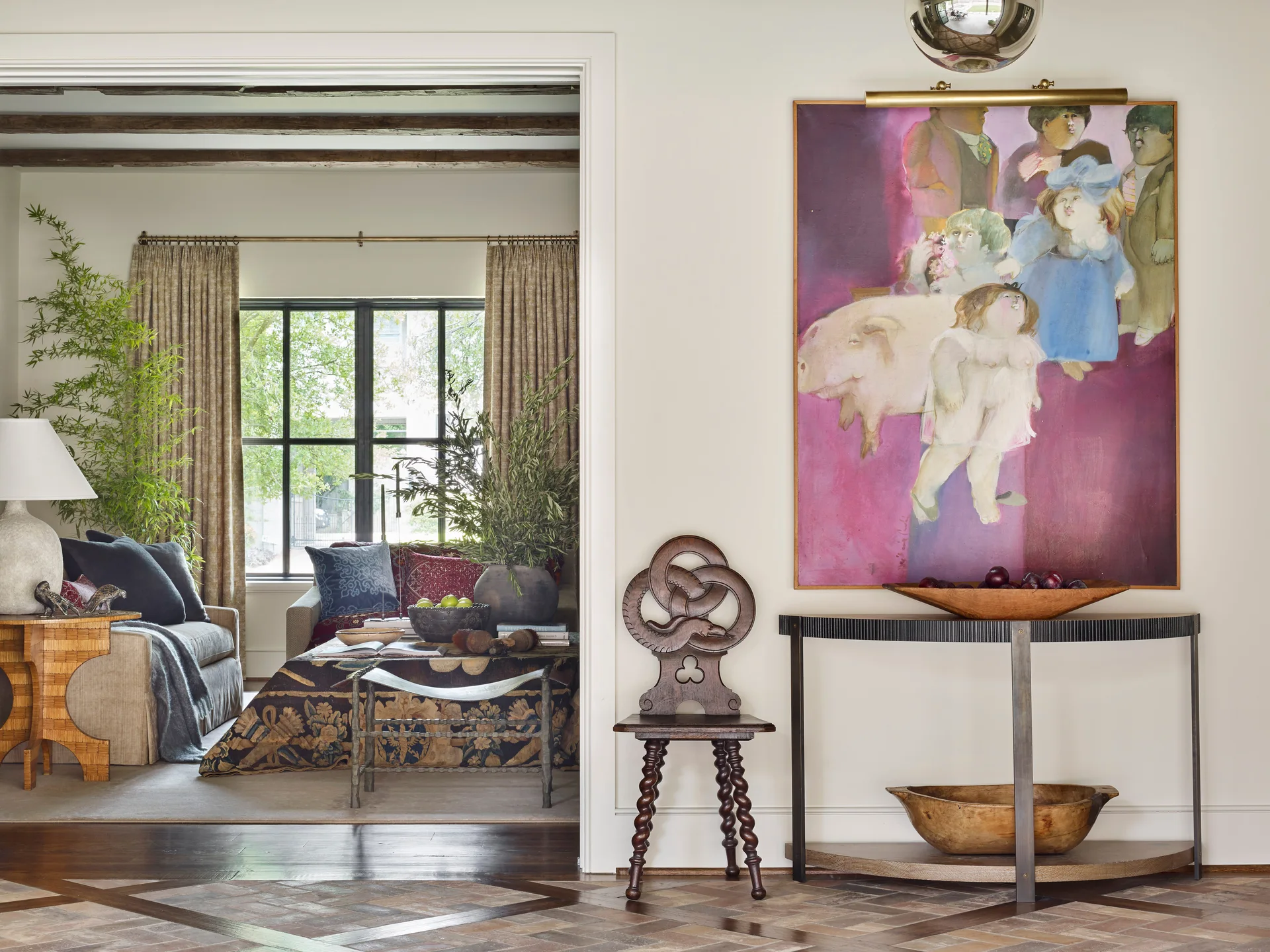 A view through a wide doorway looking toward a living room, with a large magenta painting hanging above a dark console table in the foreground.