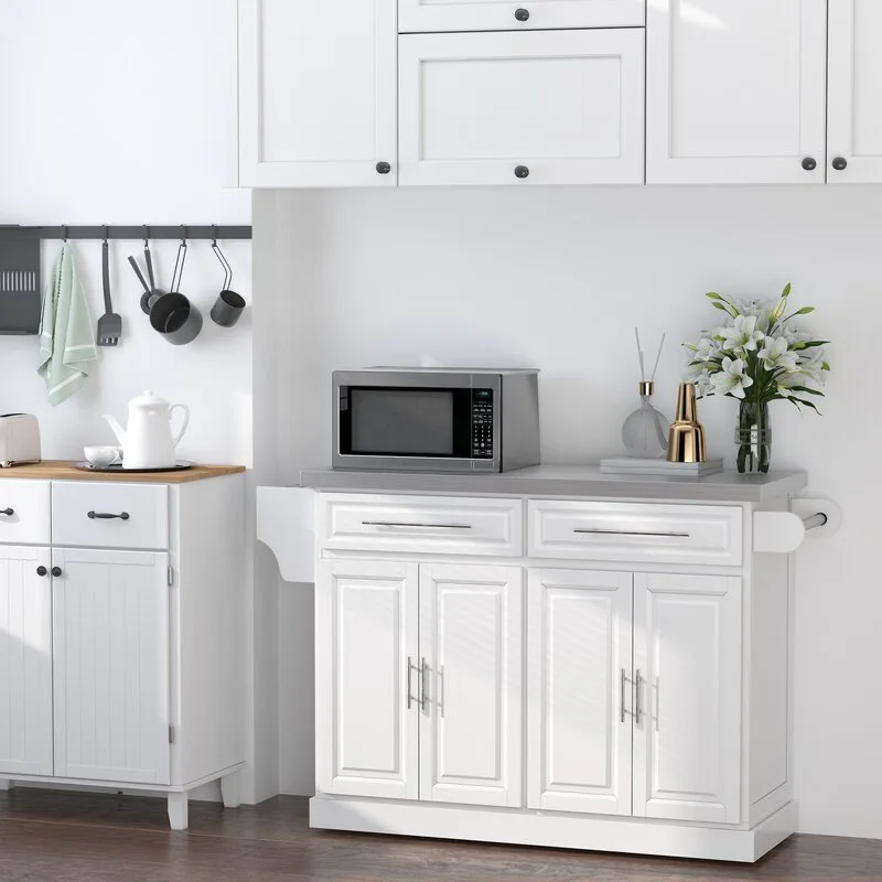 A white kitchen island with a grey countertop stands on dark wood floors next to white storage cabinets and a hanging utensil rack.