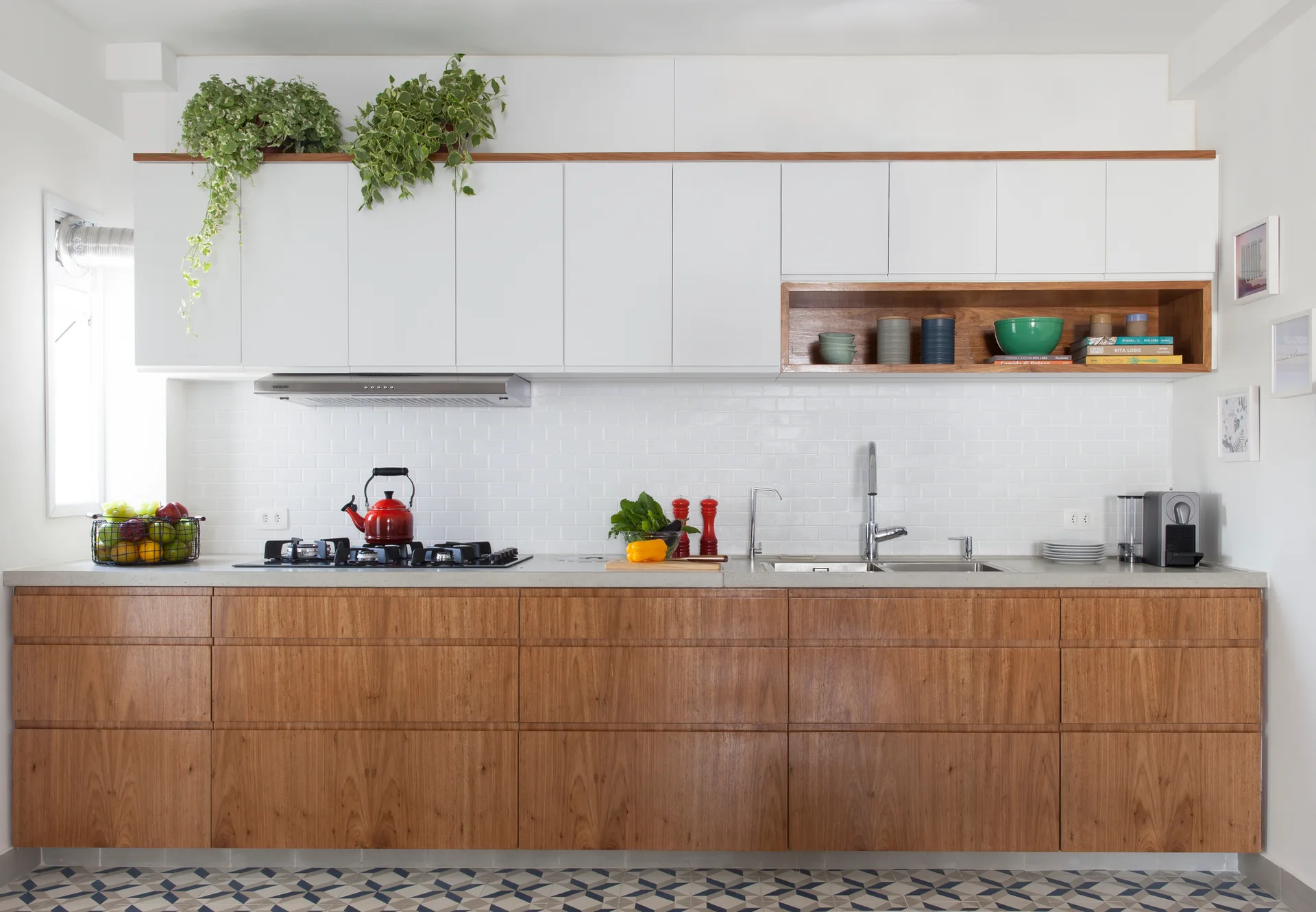A modern residential kitchen features flat white upper cabinets, wood lower cabinets, white subway tile backsplash, and a blue geometric patterned floor.