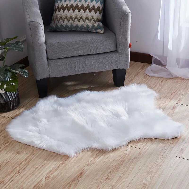 A shaggy white faux fur area rug lies on a light wood floor in front of a grey upholstered armchair with a patterned throw pillow.