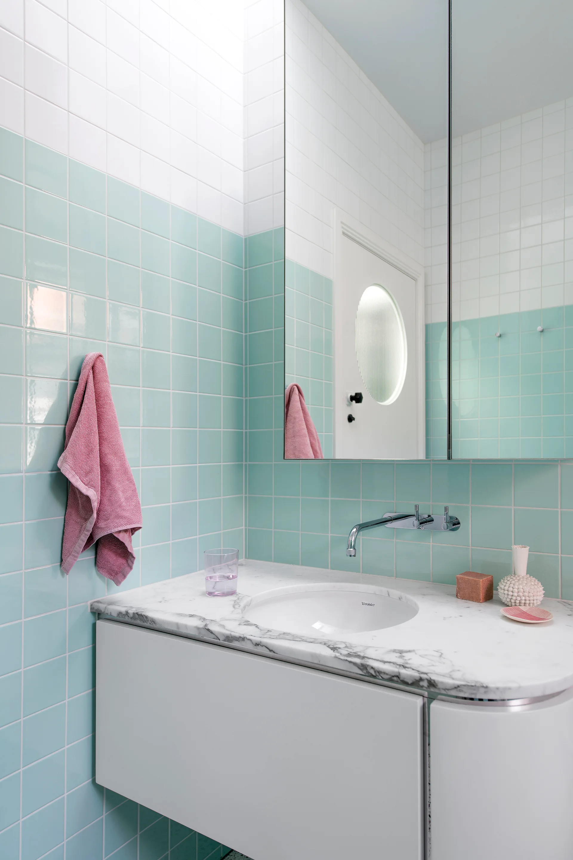 A contemporary bathroom vanity featuring mint green square tiles, a white cabinet with a marble countertop, and a wall-mounted chrome faucet.