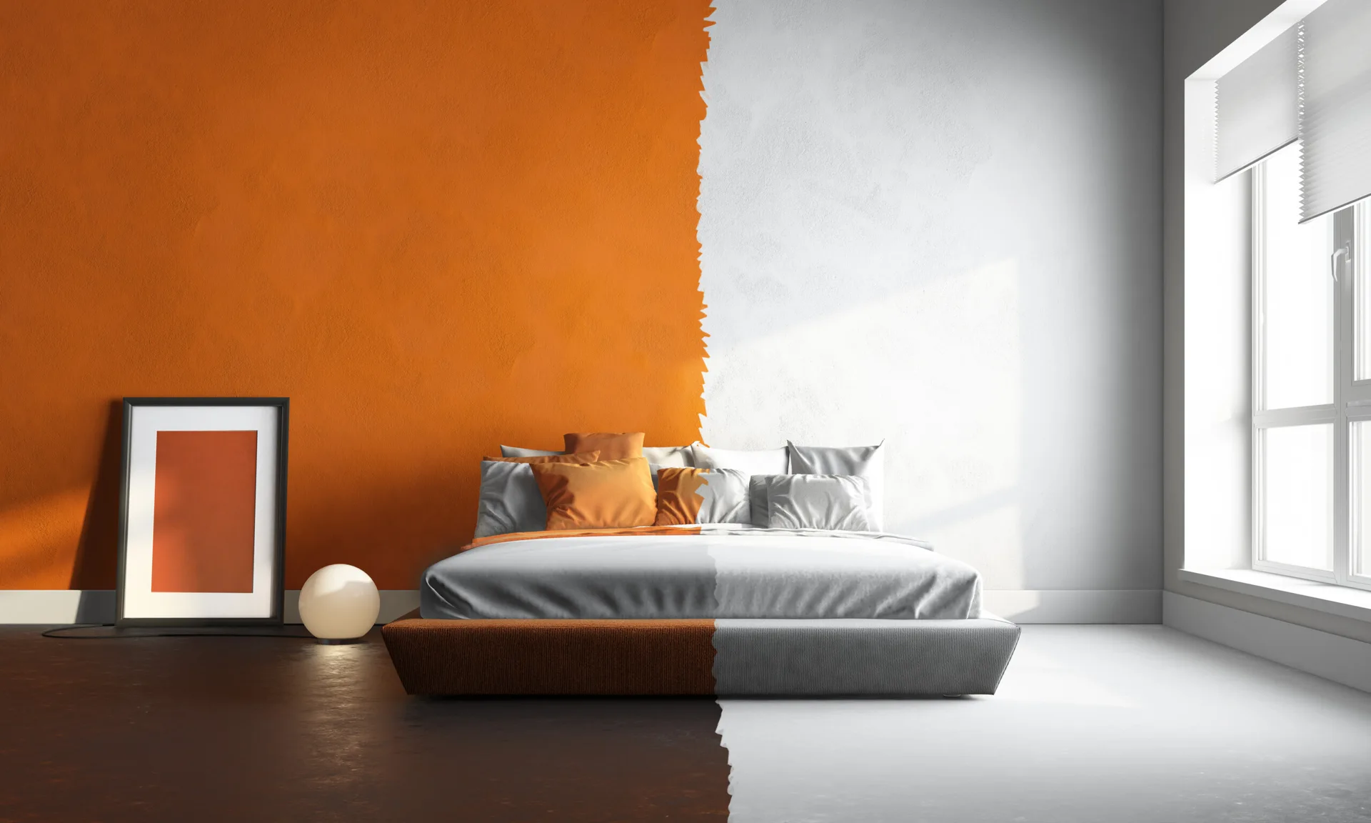 A minimalist bedroom features a low-profile platform bed against a wall split vertically down the middle between bold orange and stark white.