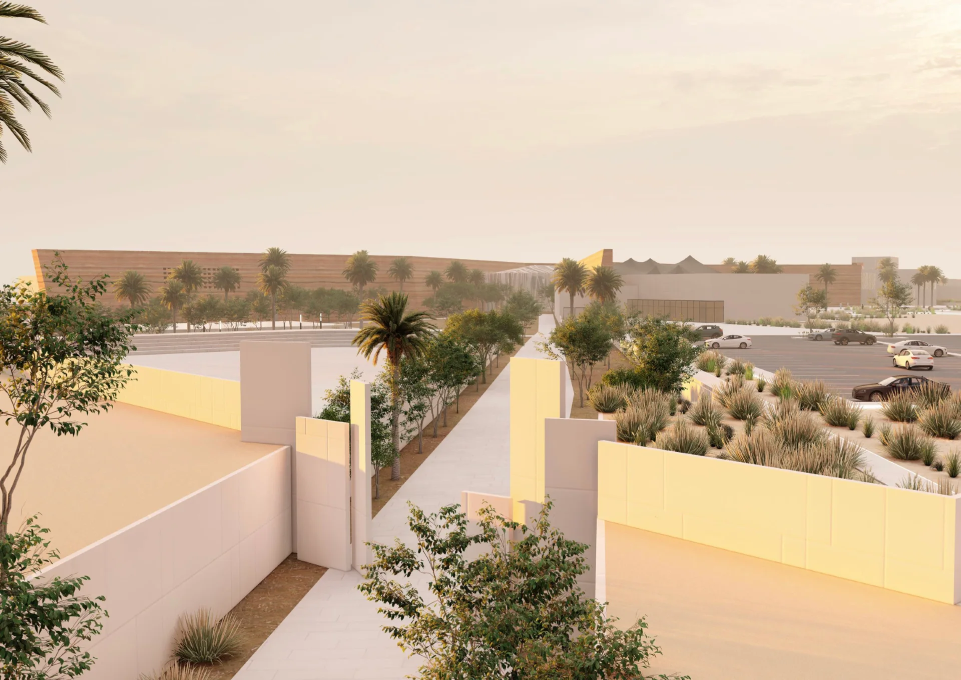 A paved pathway curves between modern white concrete walls, palm trees, and low desert plants under a warm golden dusk sky.