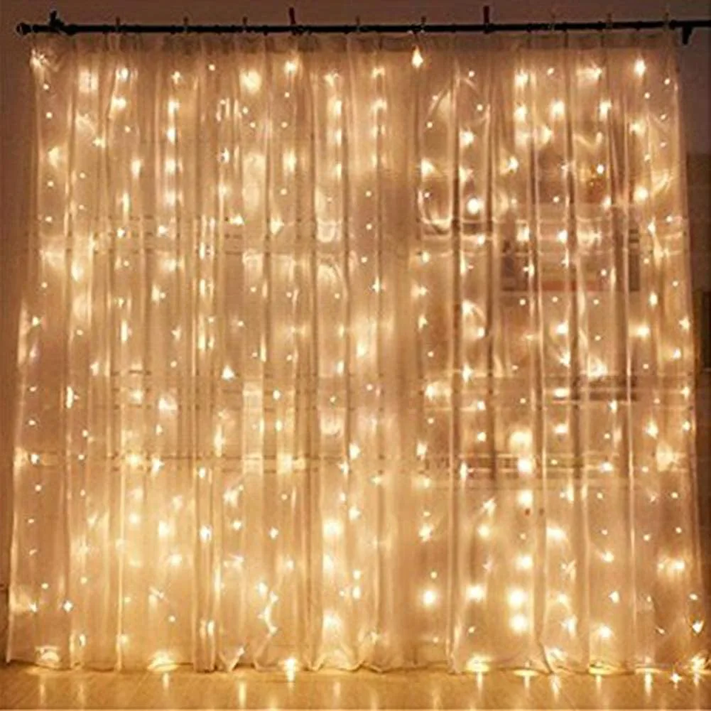 Vertical strings of warm glowing fairy lights hang behind a sheer white curtain on a black curtain rod.