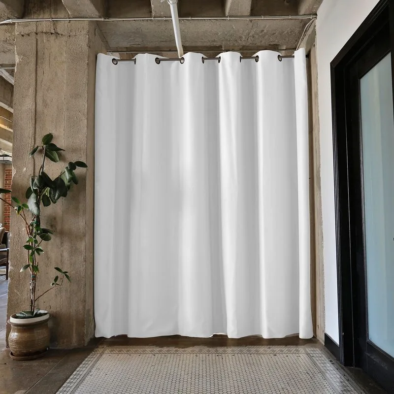 A white grommet curtain hangs between raw concrete columns over a patterned tile floor in an industrial-style interior.