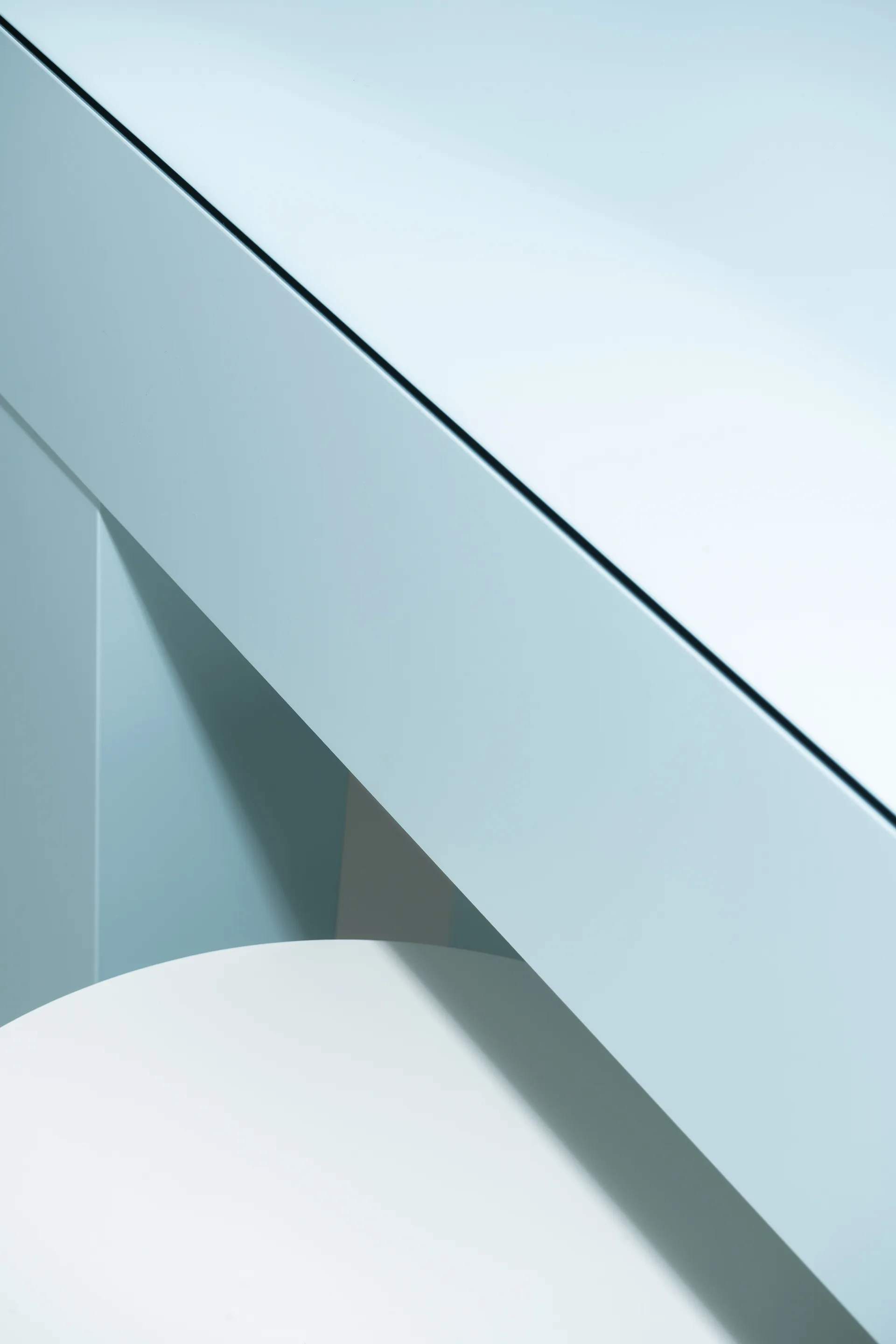 A close-up view of intersecting light blue matte cabinetry panels framing a curved white tabletop.