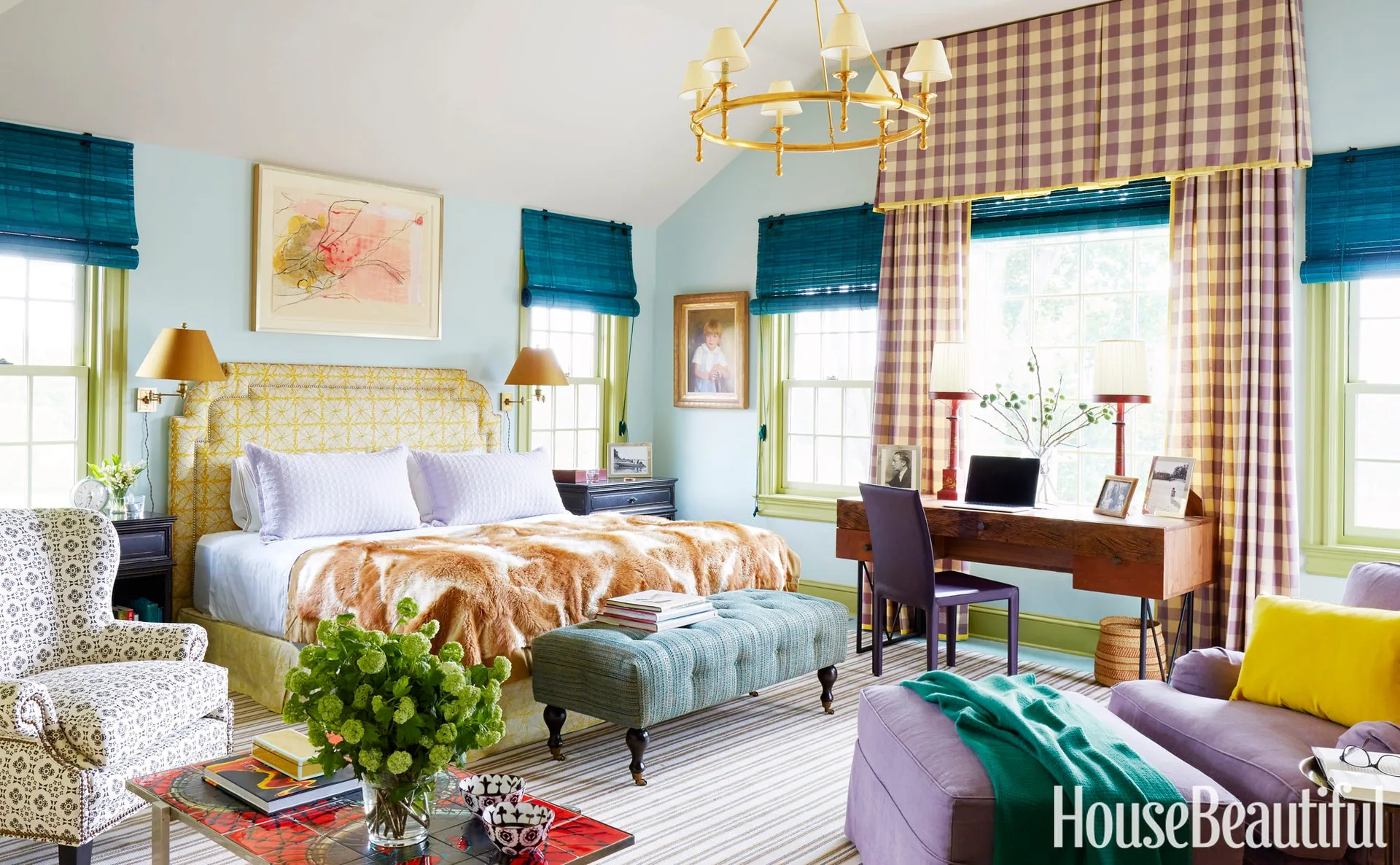 A light blue eclectic bedroom features a yellow patterned headboard, a wooden desk under a window with gingham curtains, and a striped rug.