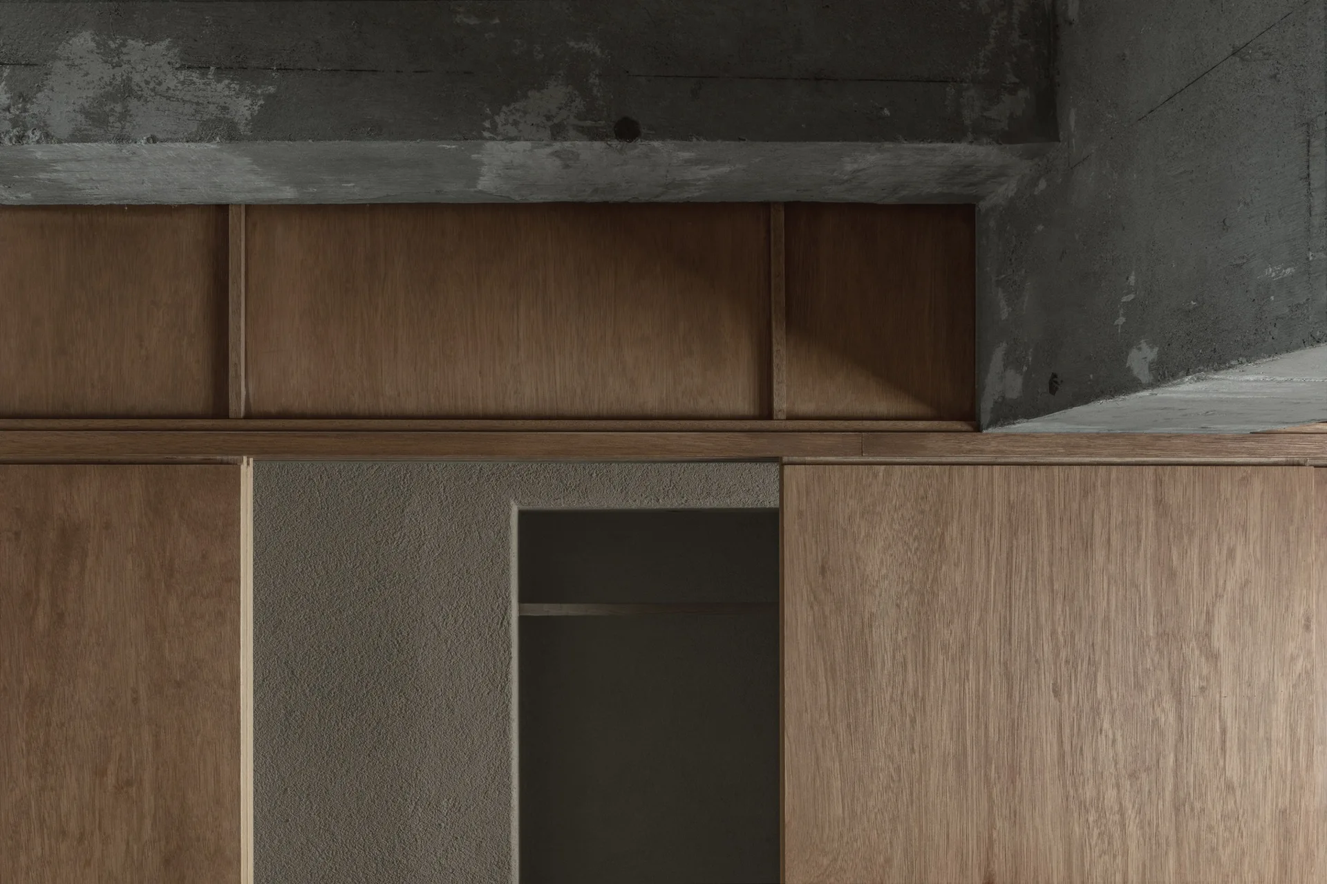A close-up view of warm-toned wood wall paneling meeting a rough, gray concrete ceiling beam above a recessed alcove.