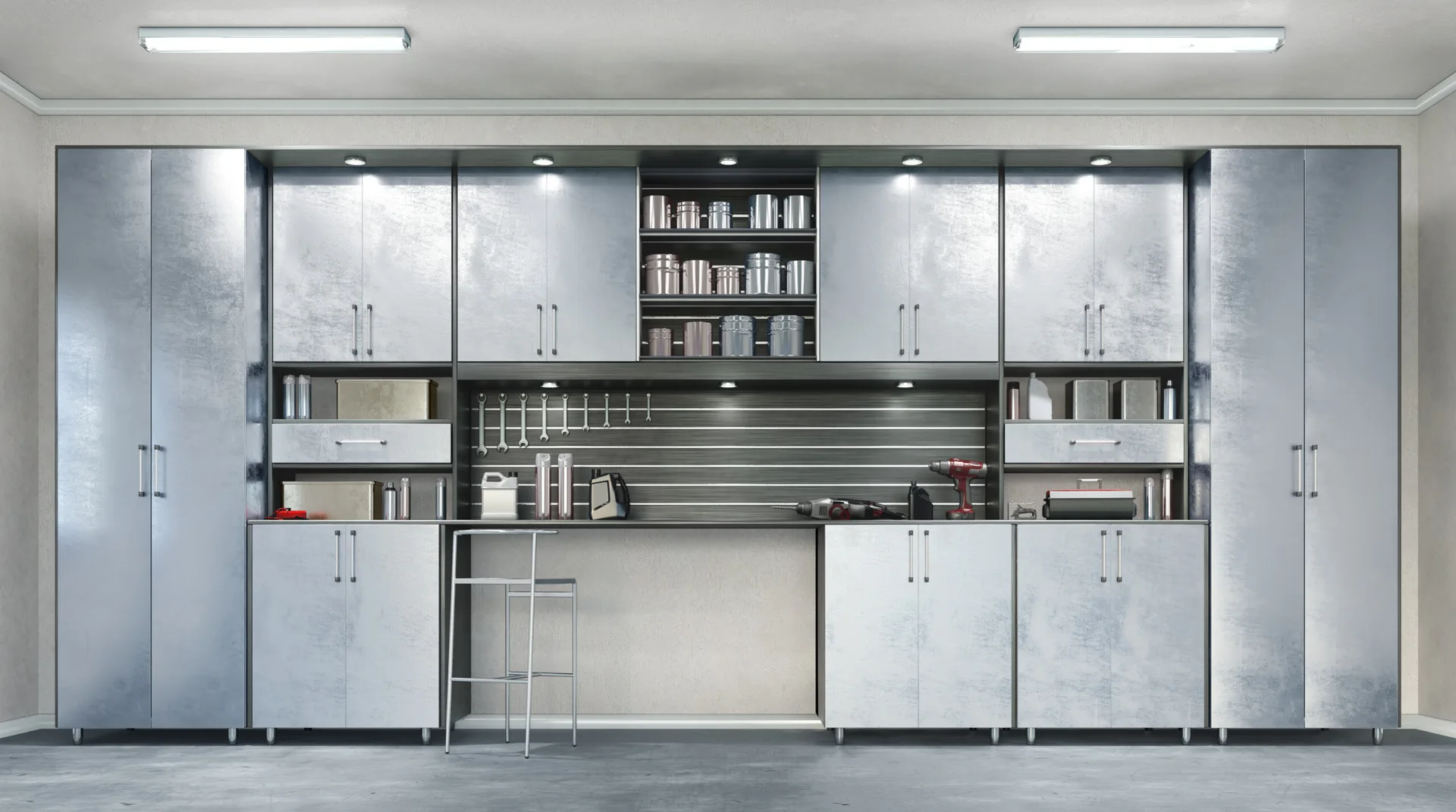 A symmetrical setup of brushed metal garage cabinets features an integrated workbench with a slotted tool wall and a steel stool.