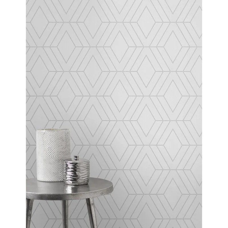 A small round metal accent table with a white textured vase and silver jar sits in front of a wall with grey geometric diamond pattern wallpaper.