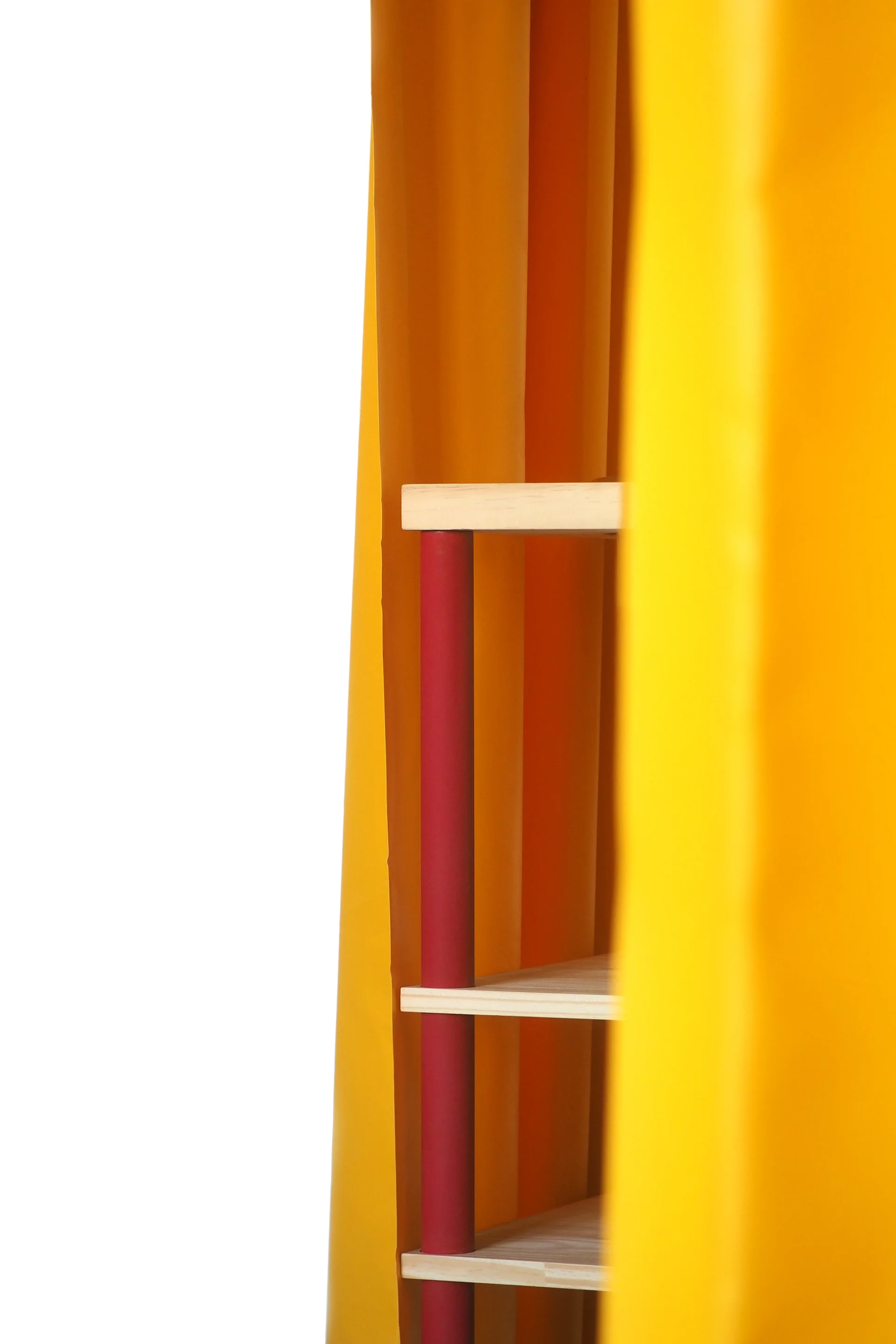 A close-up of a wooden modular shelf with red cylindrical posts partially obscured by draped bright yellow fabric against a white background.
