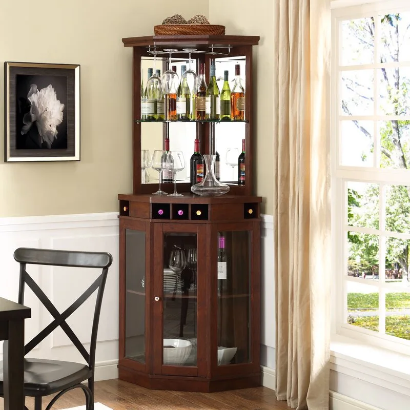 A dark wood corner bar cabinet with a mirrored hutch stands in a dining room near a window with beige curtains.