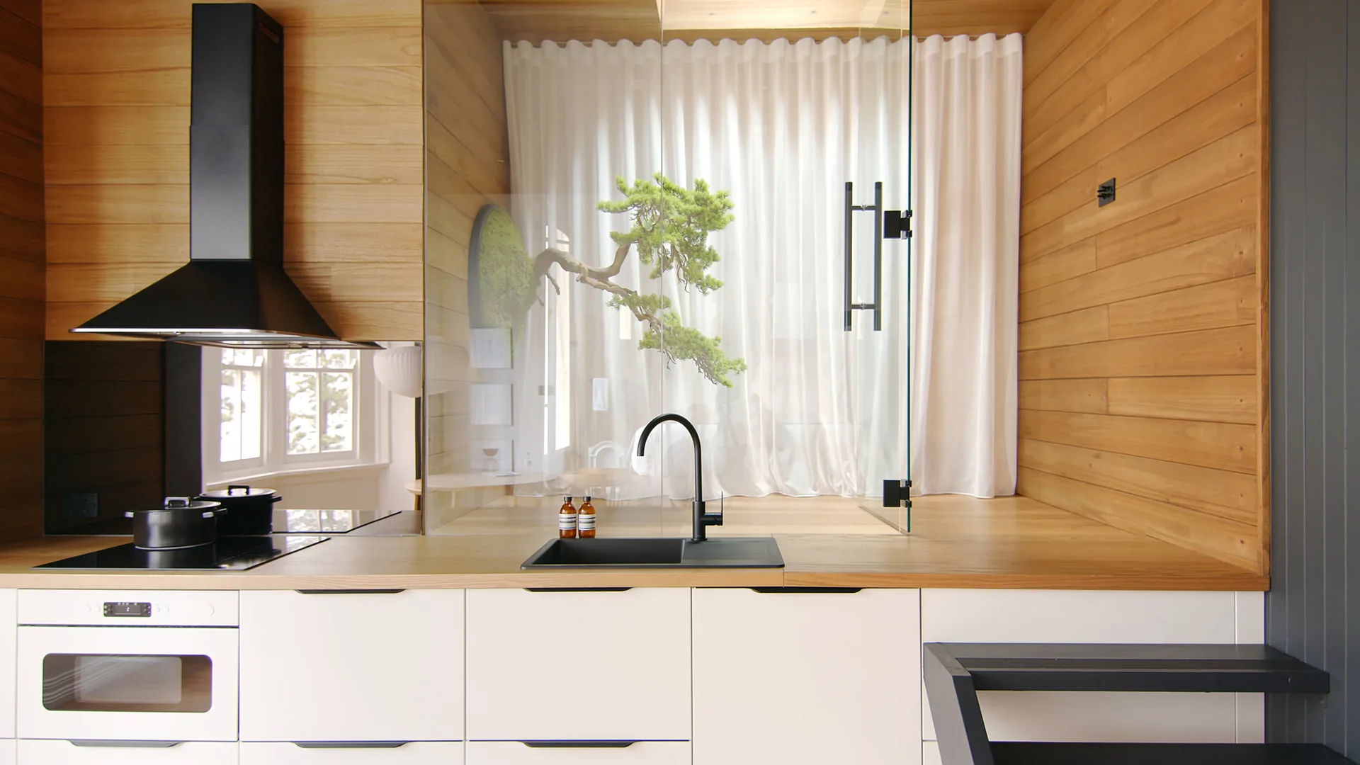 A modern kitchen features white lower cabinetry, light wood plank walls, a black range hood, and a glass-enclosed bonsai tree.
