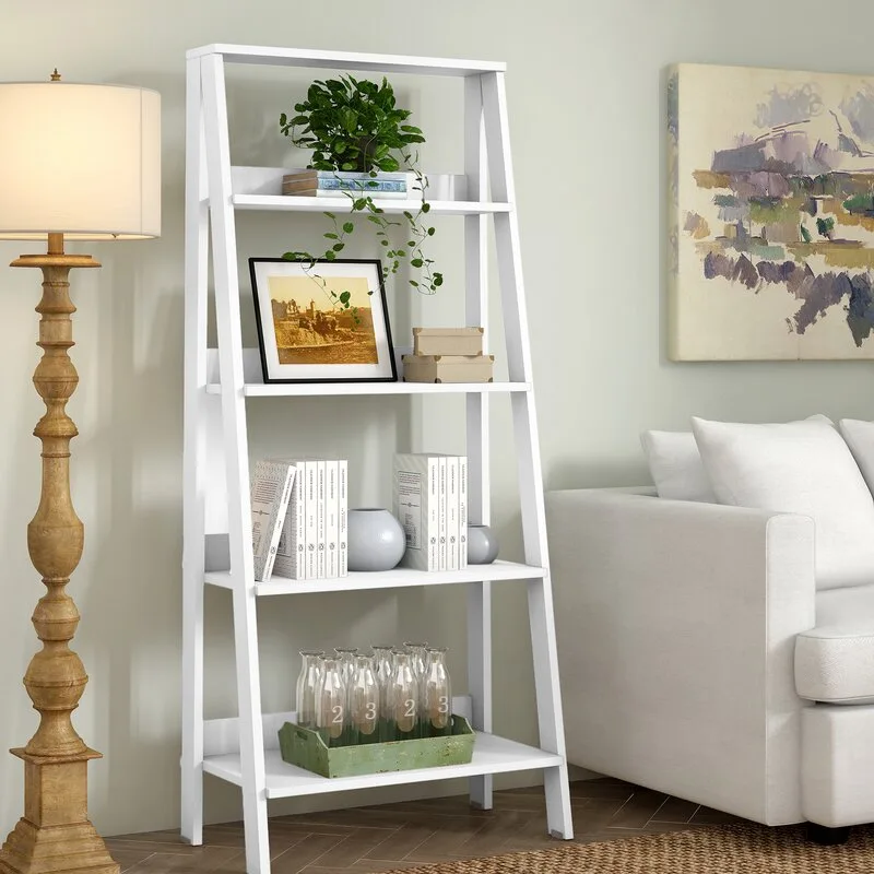 A five-tier white ladder bookshelf styled with books, plants, and glass bottles sits next to a wooden floor lamp and a white sofa.